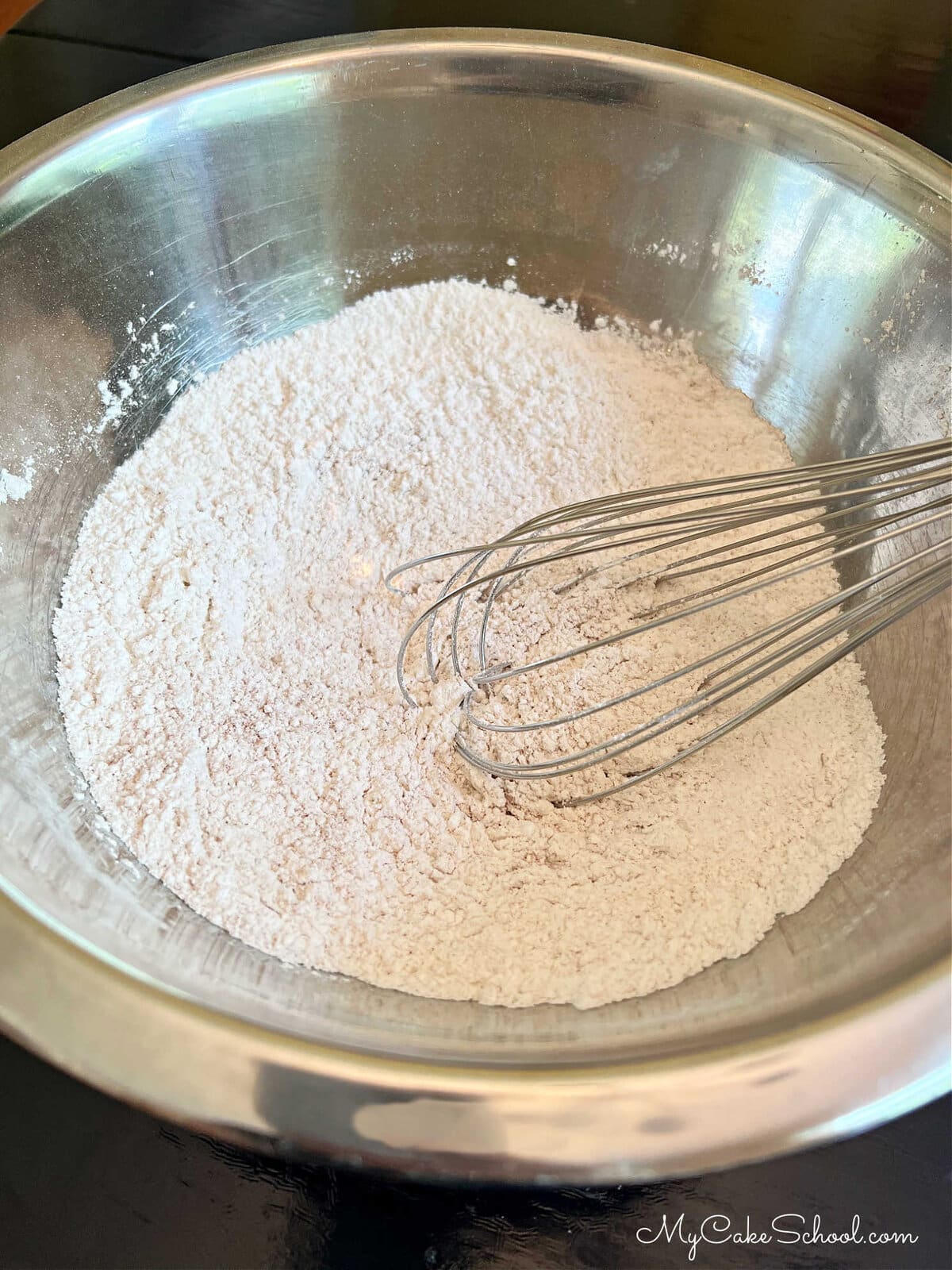 Bowl of dry ingredients for honey cake with whisk