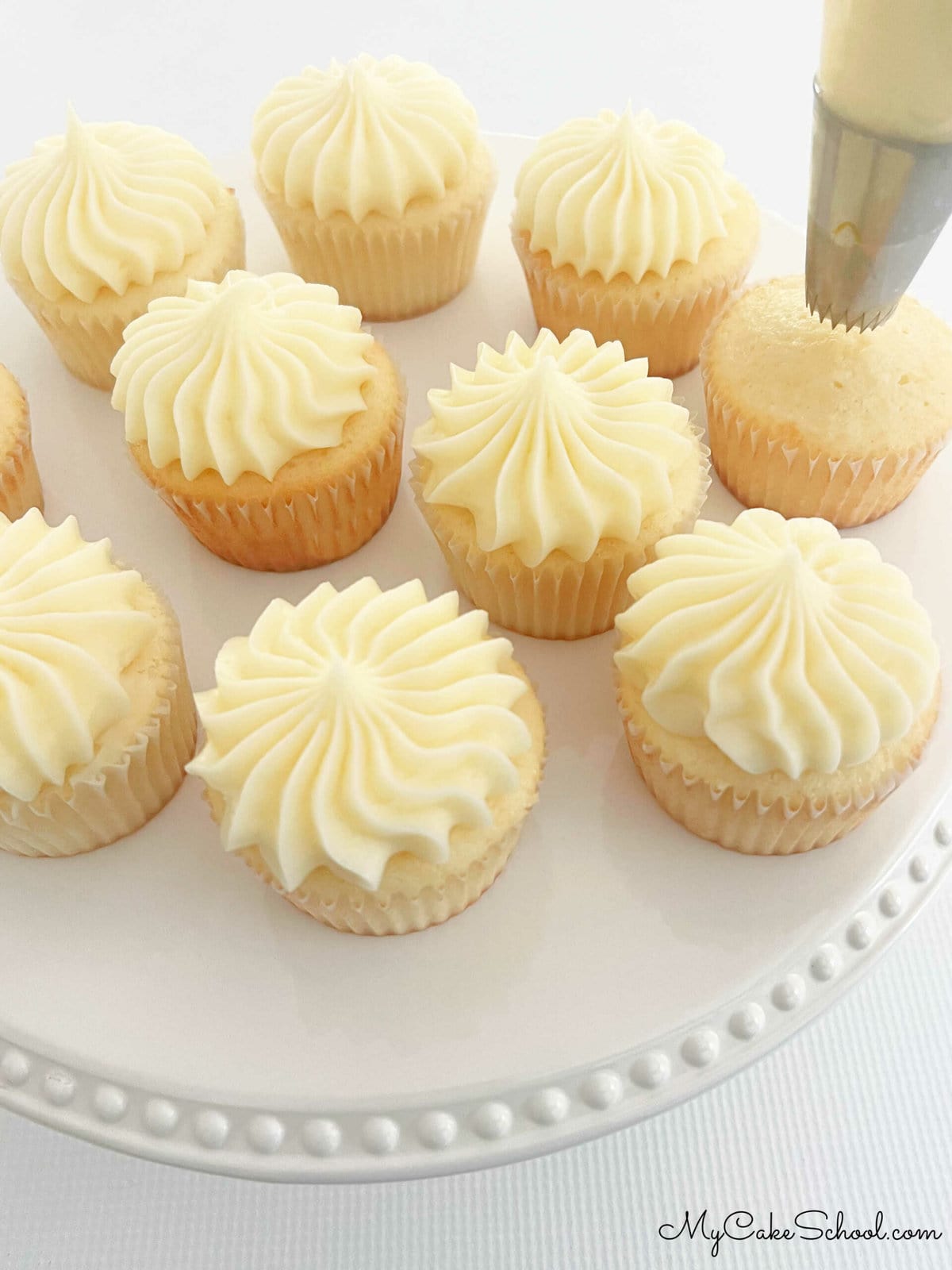 Piping lemon cream cheese frosting onto the cupcakes 