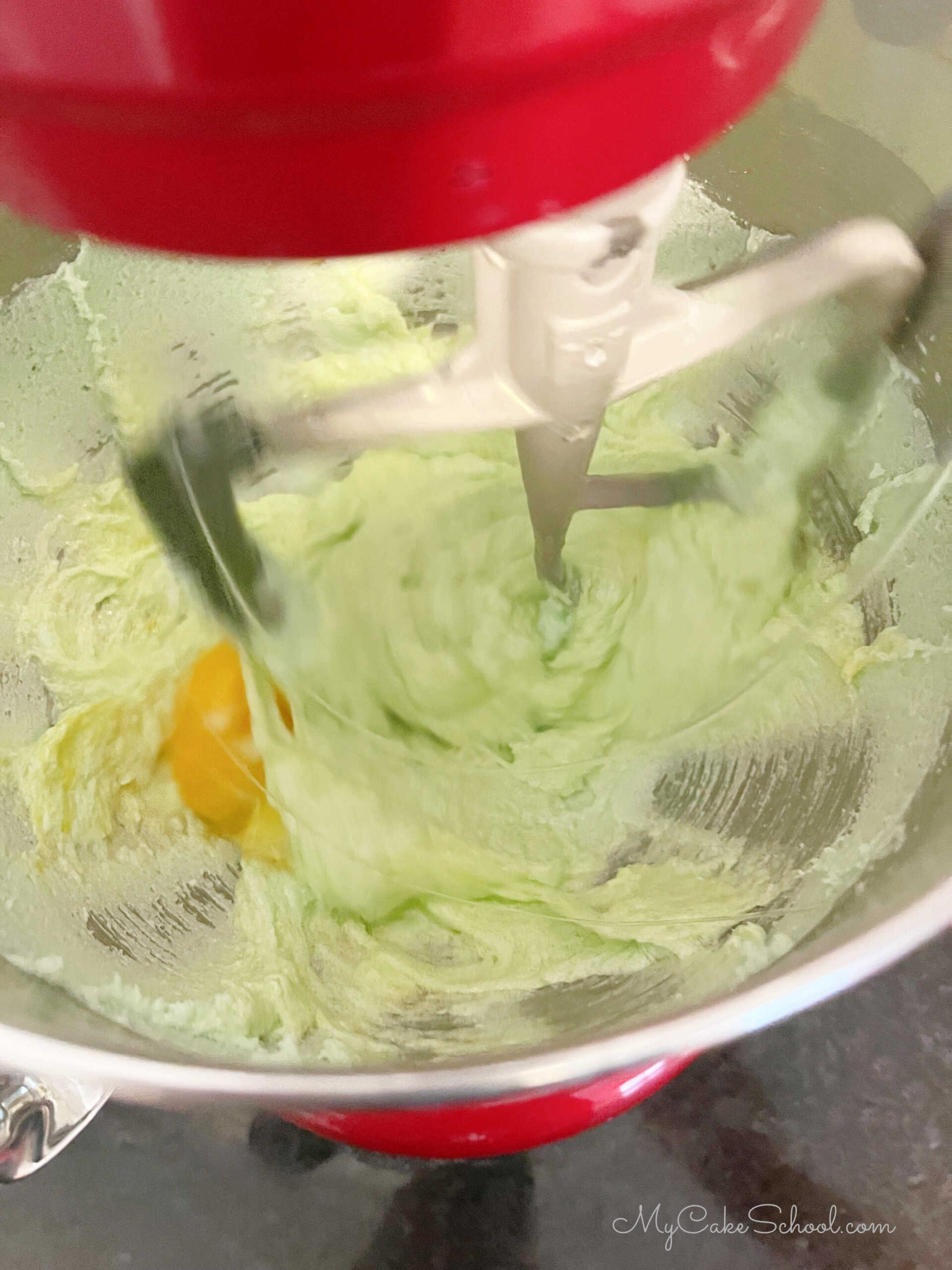 Adding eggs to the butter, sugar, and jello mixture.