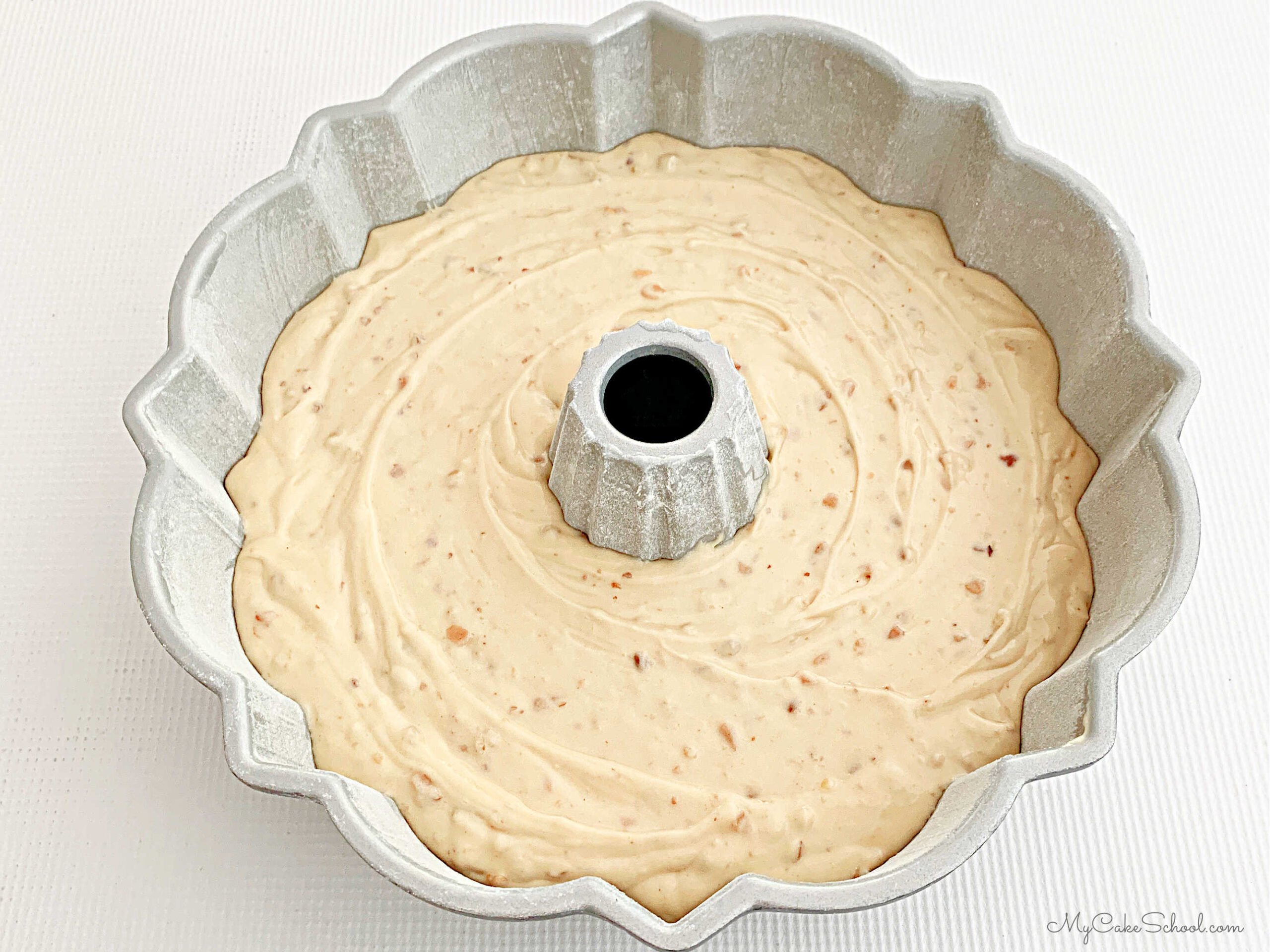 Prepared bundt pan filled with toffee pecan cake batter