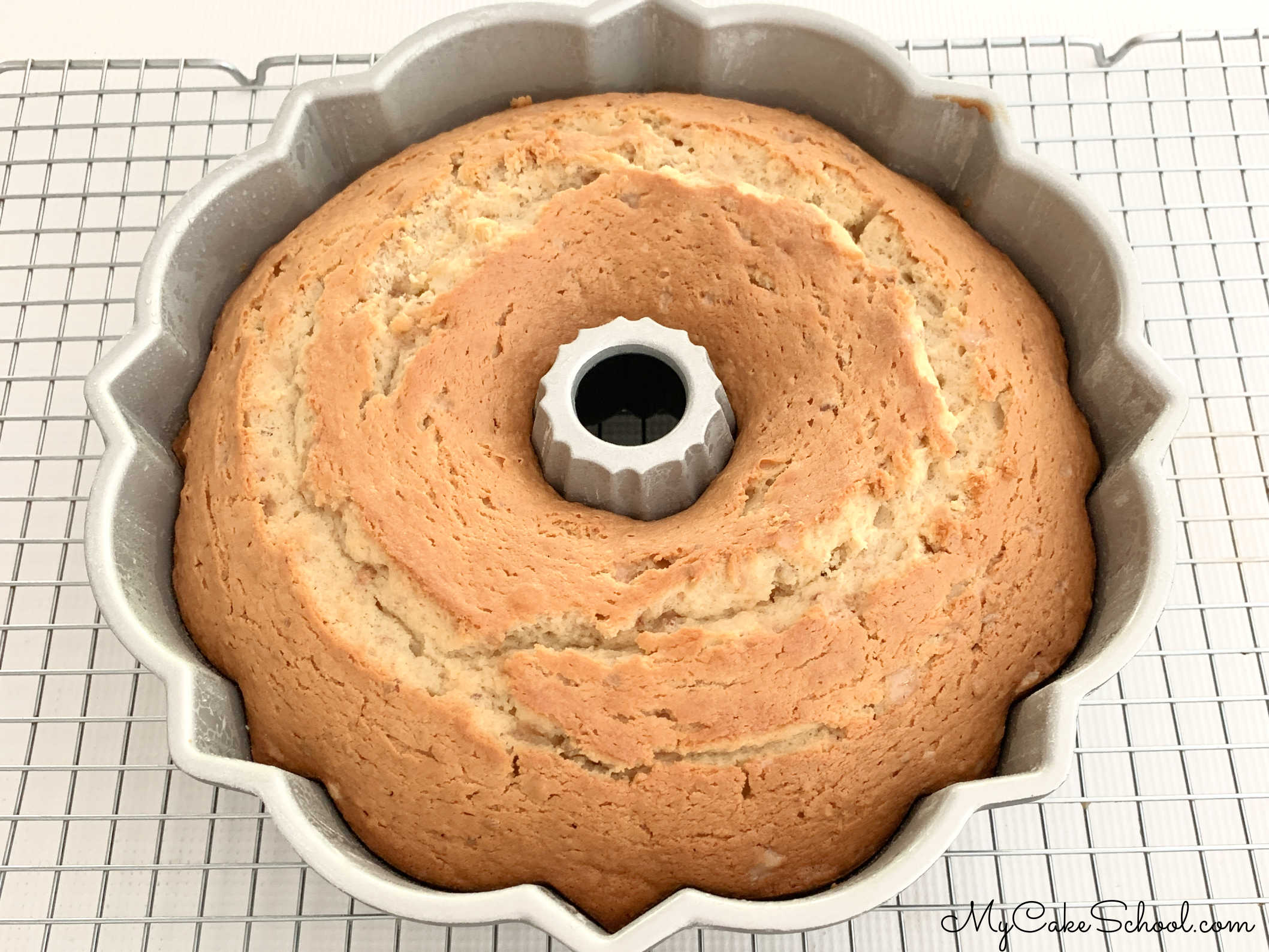 Freshly baked Toffee Pecan Bundt Cake in pan, cooling on wire rack