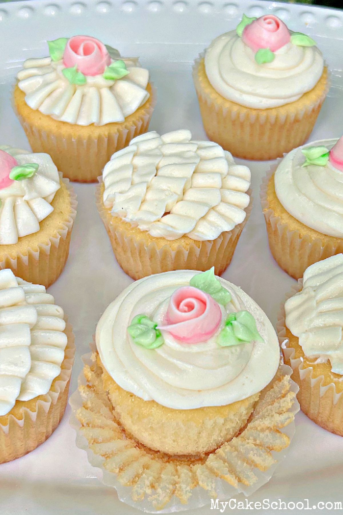 Platter of scratch vanilla cupcakes, decorated with buttercream ruffles and roses, on a pedestal.