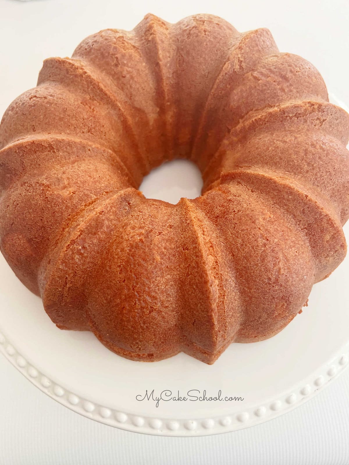 Freshly baked honey cake on white pedestal before glazing