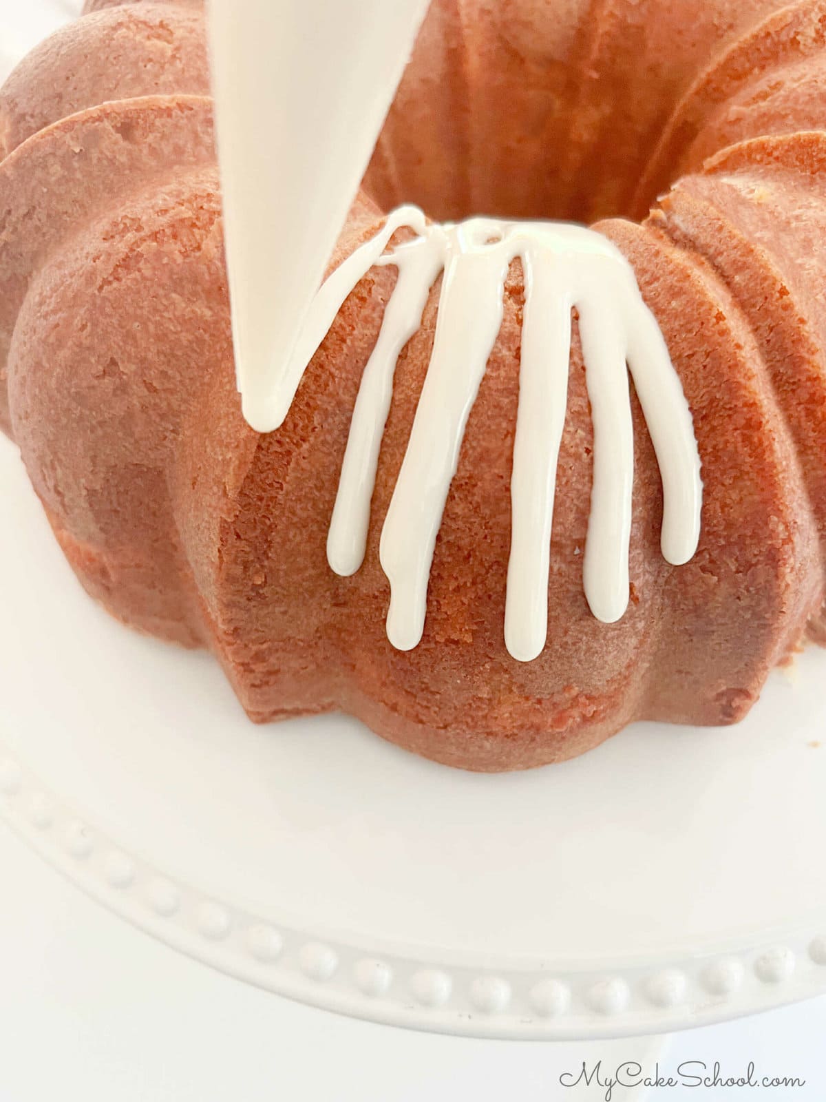 Drizzling glaze over a honey bundt cake using a piping bag