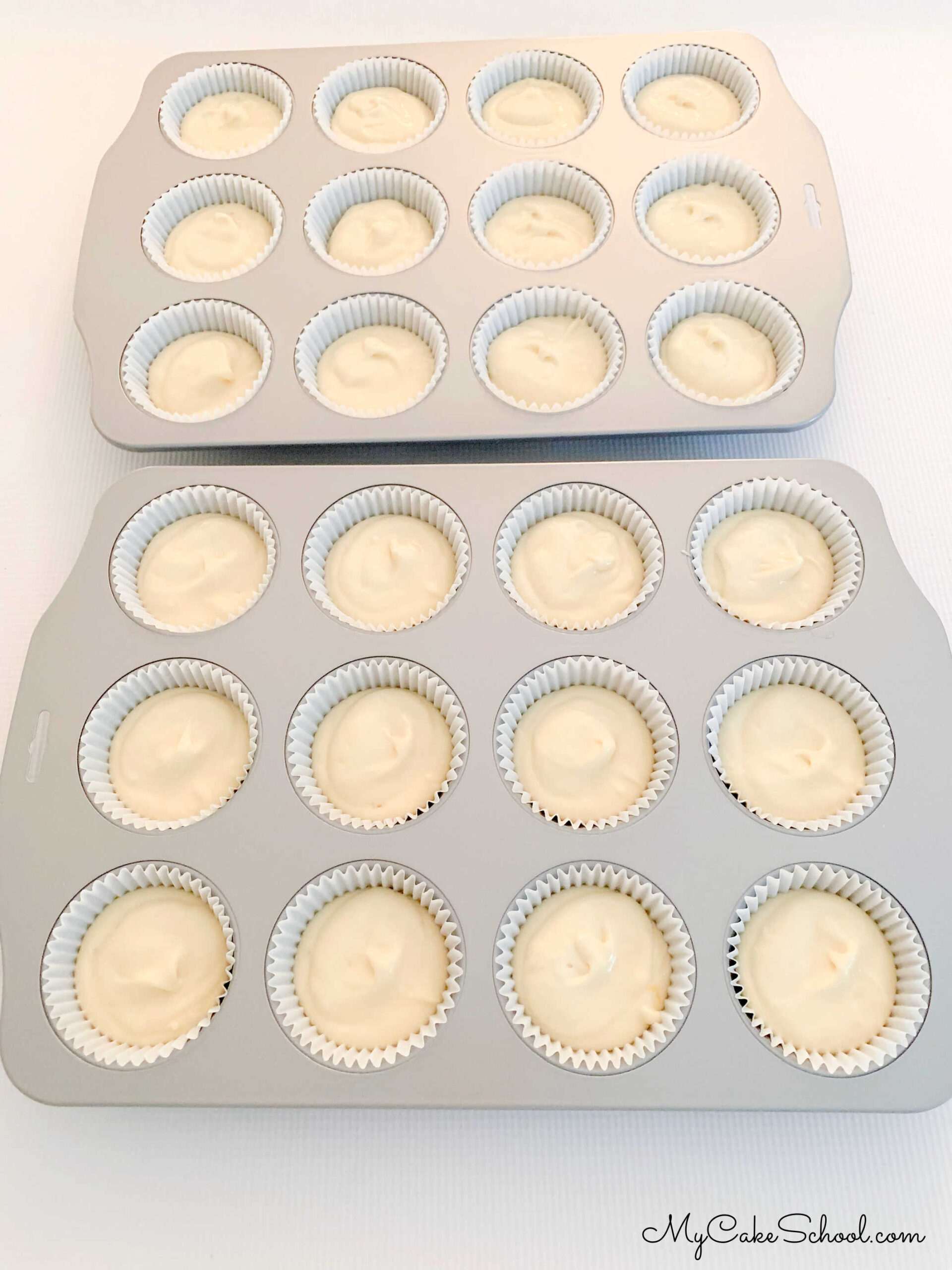 Two cupcake pans, lined with paper cupcake liners and filled with batter.