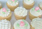 Platter of vanilla cupcakes, decorated with buttercream ruffles and roses