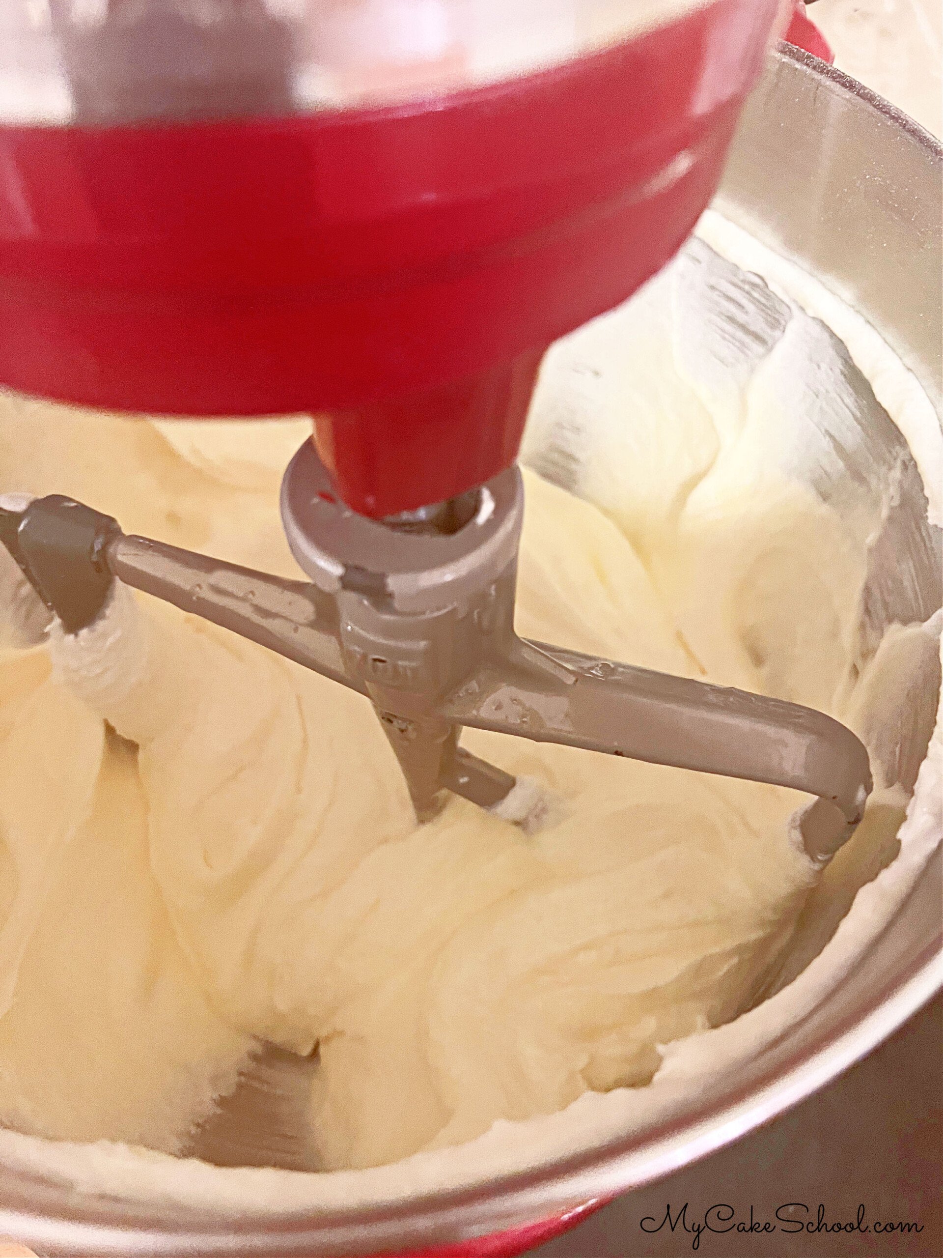 Adding eggs to cream cheese and butter mixture in mixing bowl.