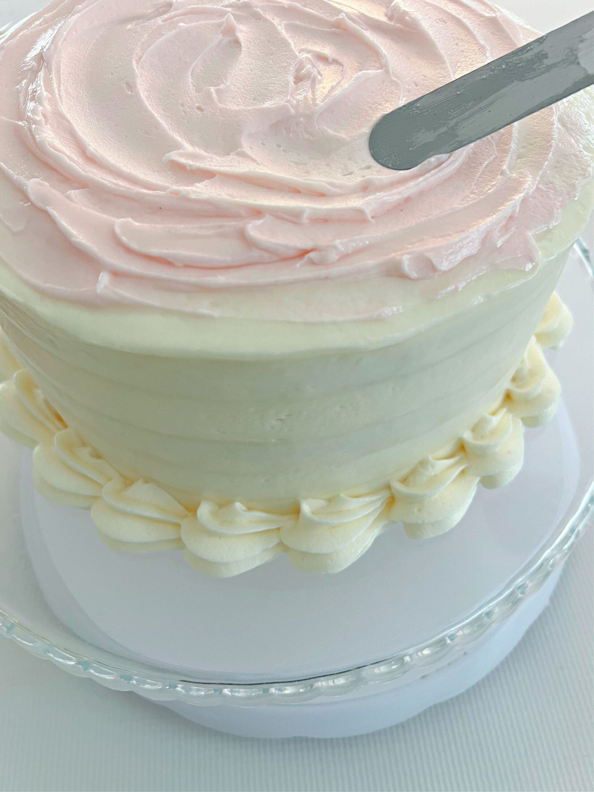 Swirling pink buttercream on top of the frosted cake.