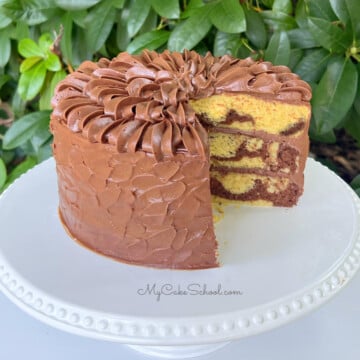 Sliced Marble Cake from cake mix, frosted with chocolate buttercream, resting on a white cake pedestal.