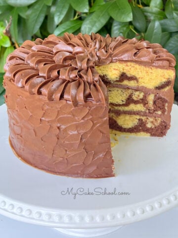 Sliced Marble Cake from cake mix, frosted with chocolate buttercream, resting on a white cake pedestal.