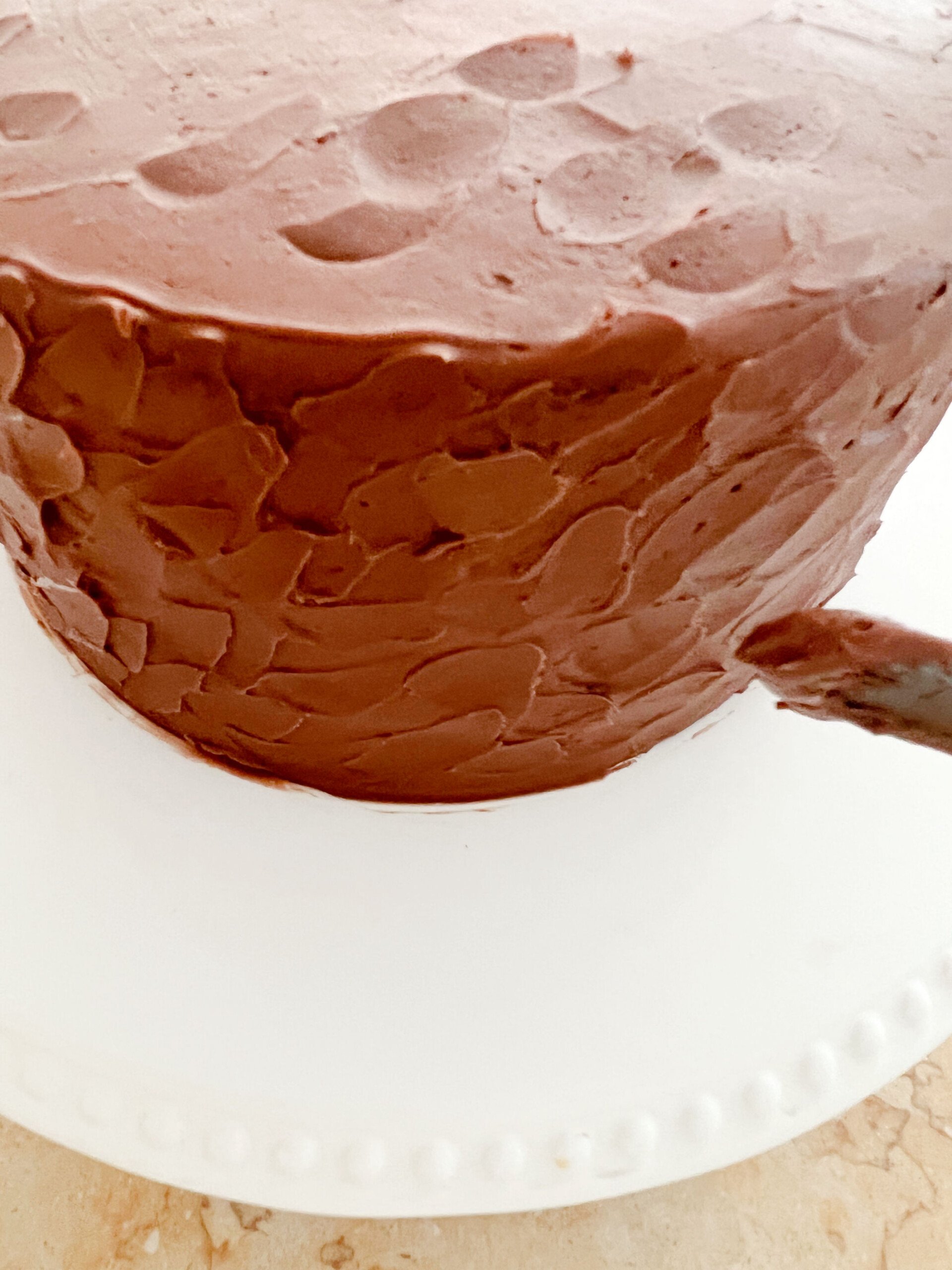 Texturing the chocolate buttercream-frosted cake with a small offset spatula.