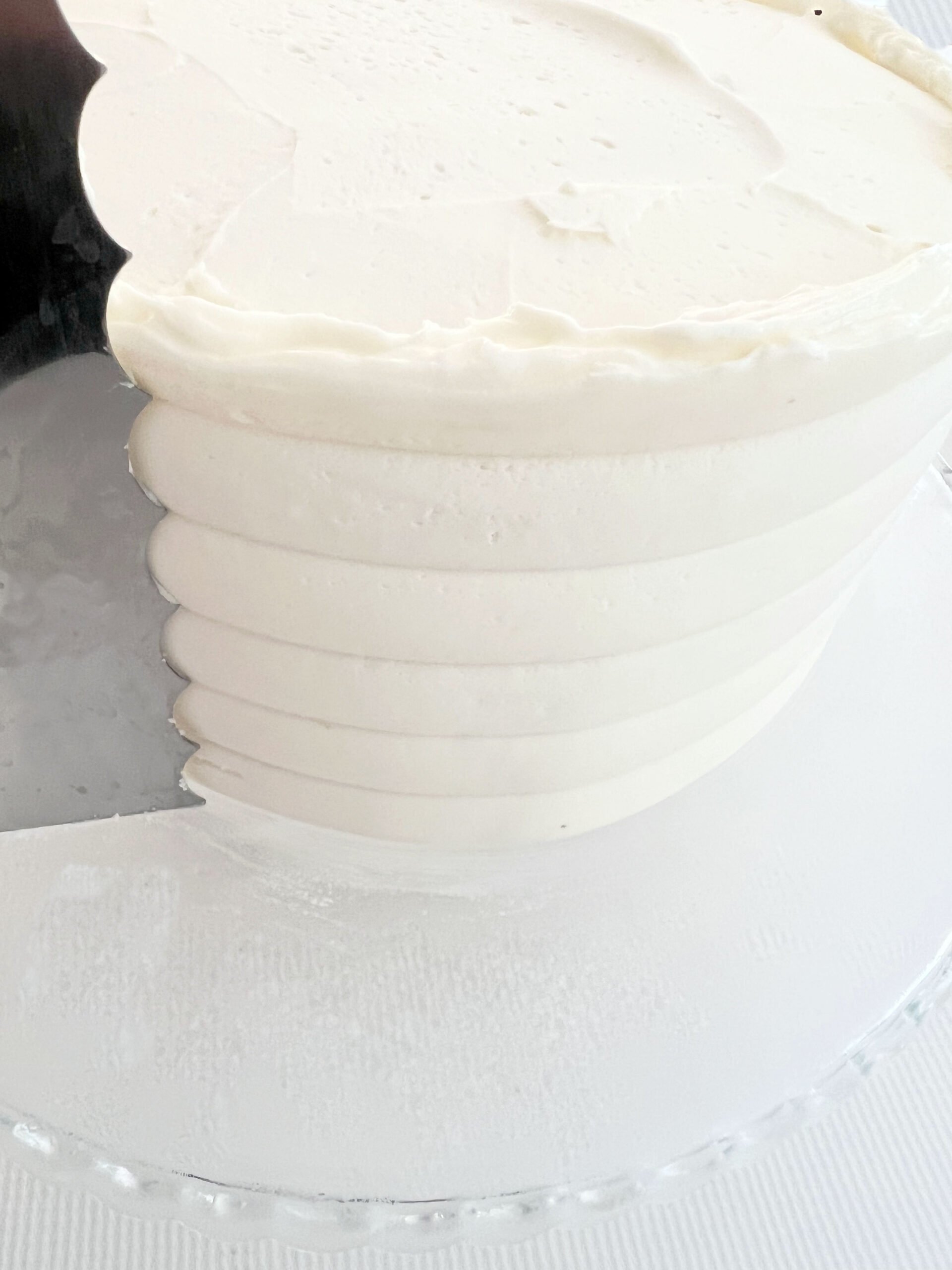 Combing the frosted cake around the sides with a cake comb.