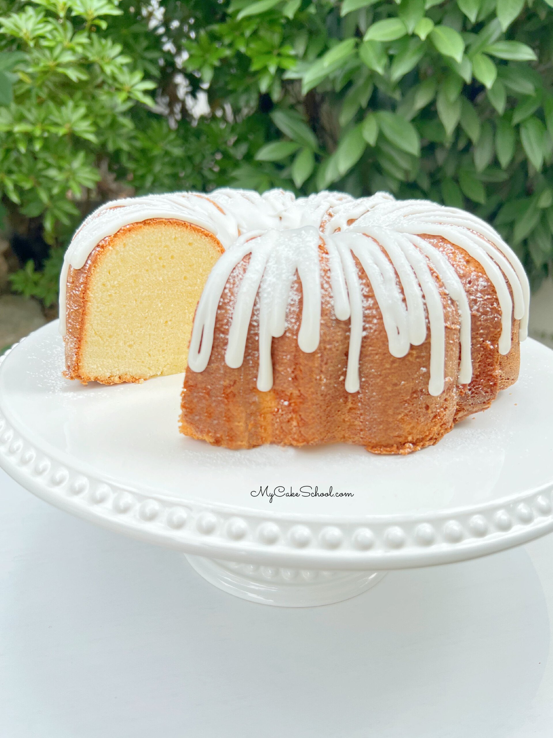 Sliced Cream Cheese Pound Cake on white pedestal.