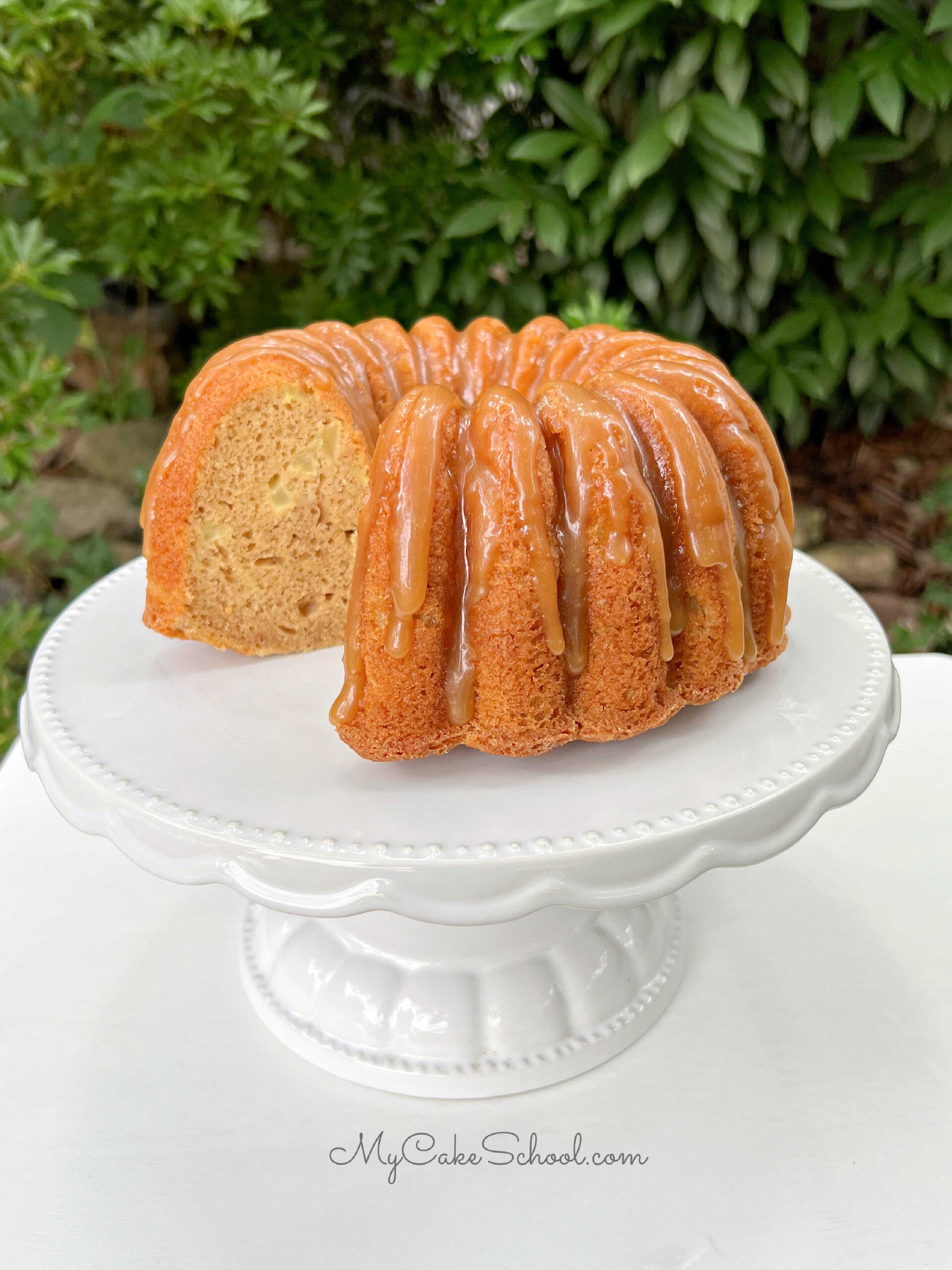 Moist, sliced Apple Bundt Cake on a white cake pedestal.