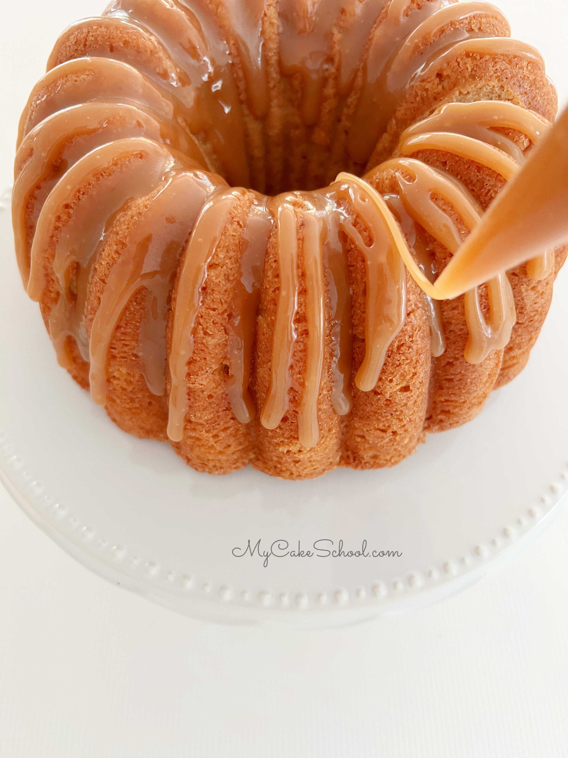Drizzling Apple Bundt Cake with simple caramel glaze, using a piping bag with the tip snipped away.