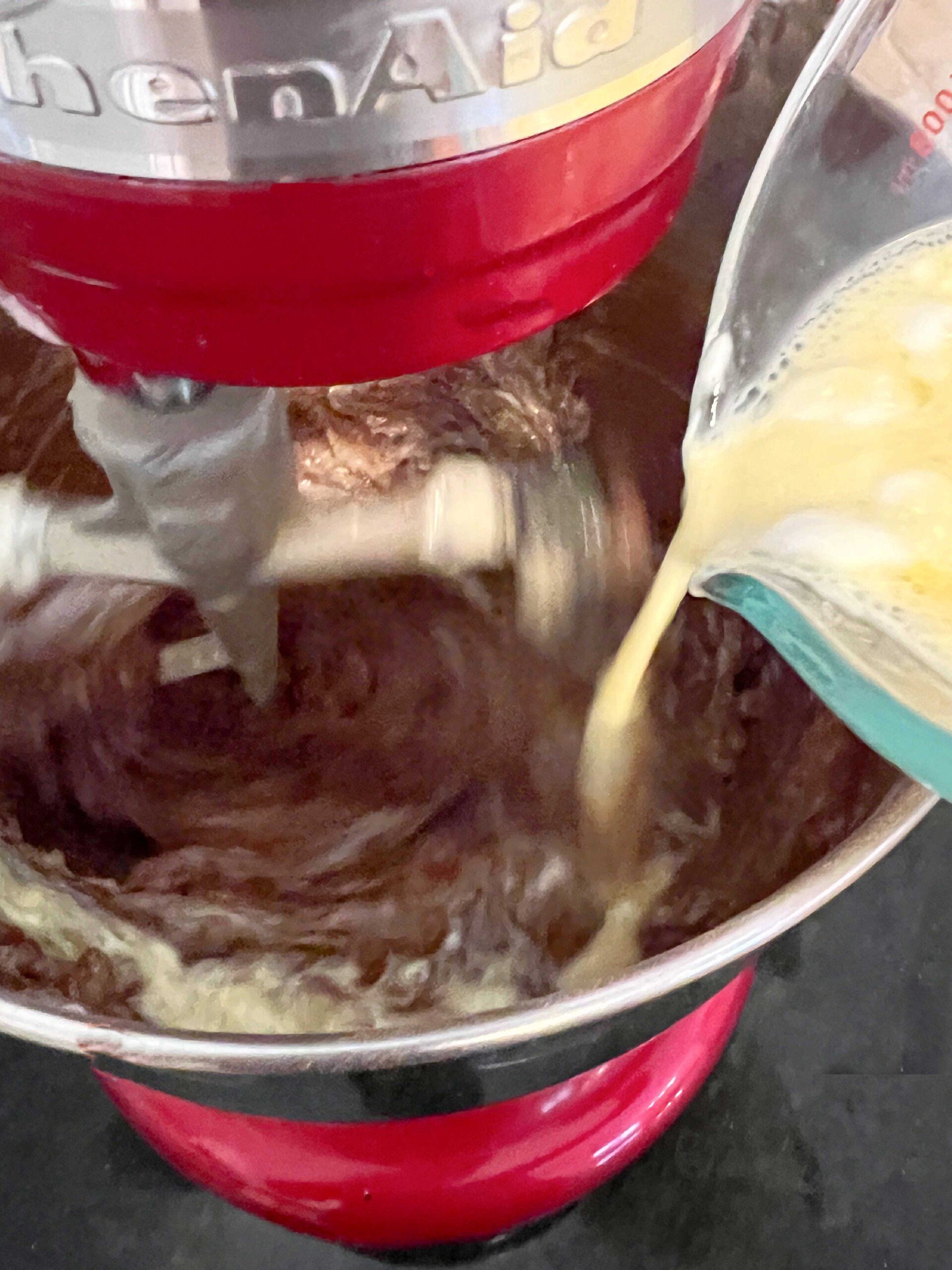 Adding egg mixture to chocolate cake batter.