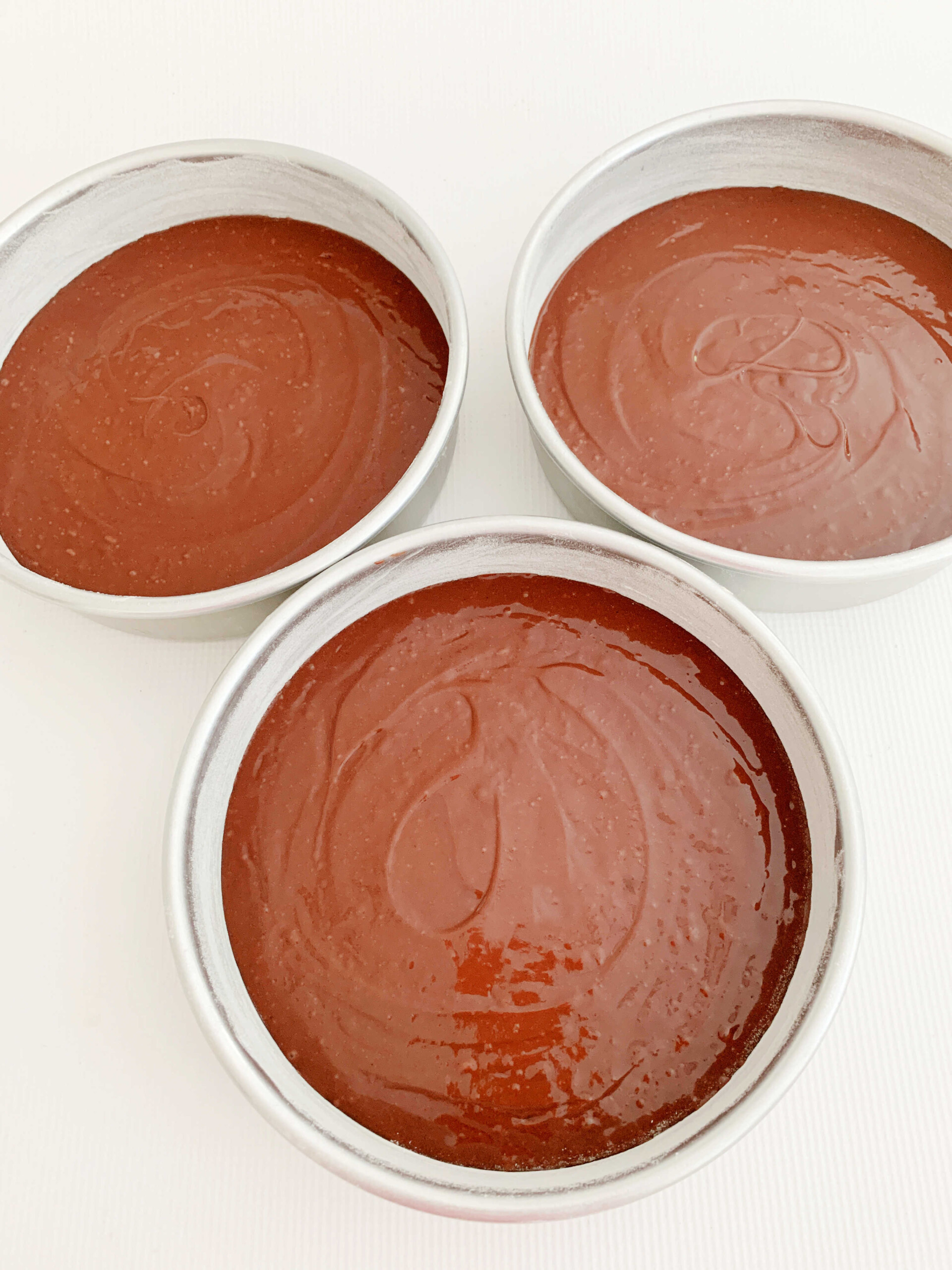 Chocolate Batter in three round cake pans.