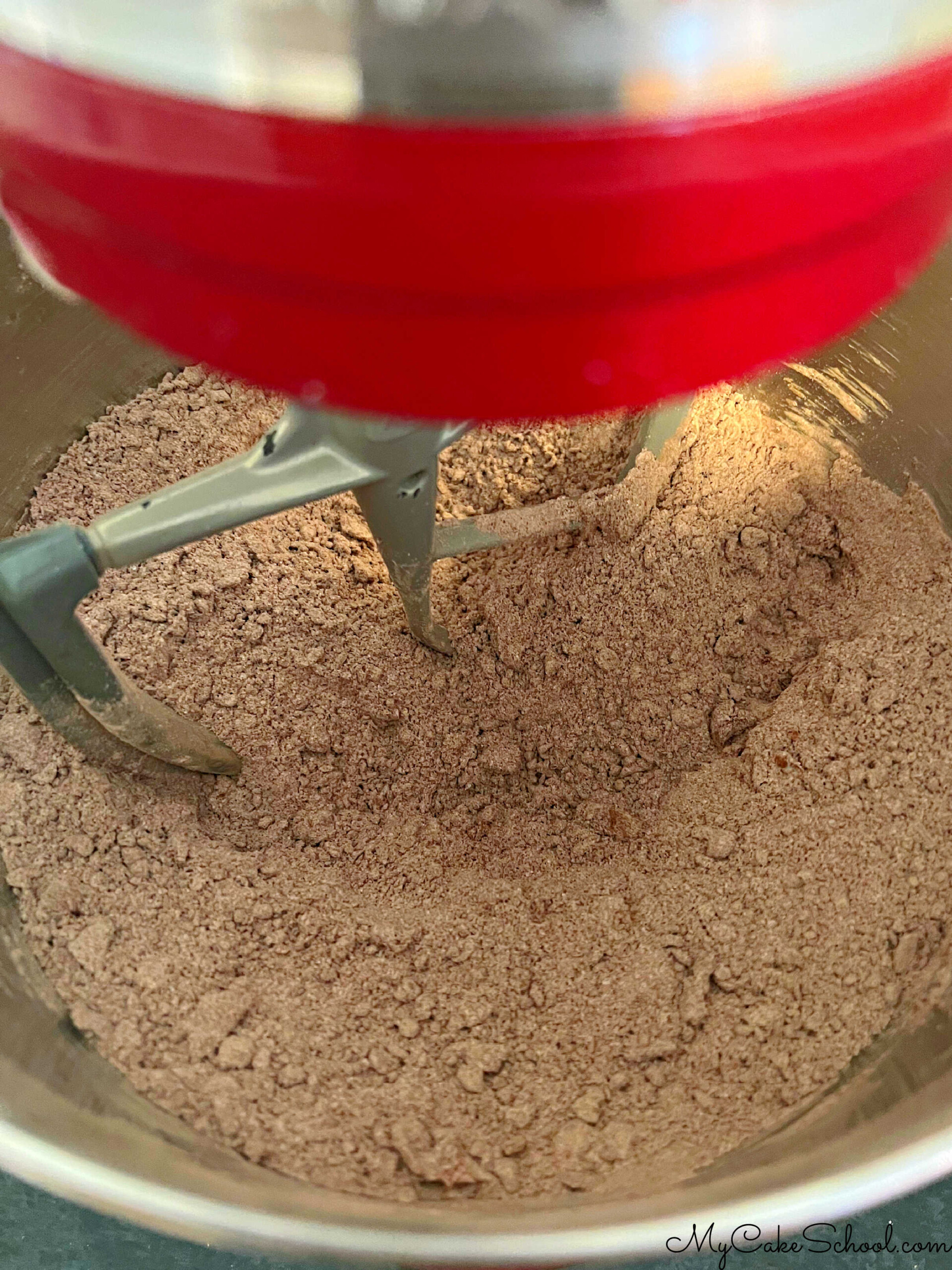 Mixing butter into dry ingredients in mixing bowl. (This is a step in the reverse creaming method of mixing.)