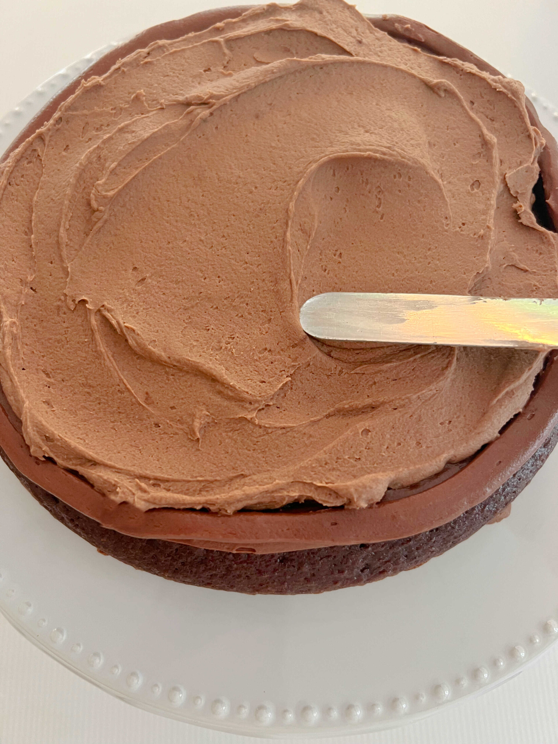 Spreading chocolate mousse filling onto cake layer.