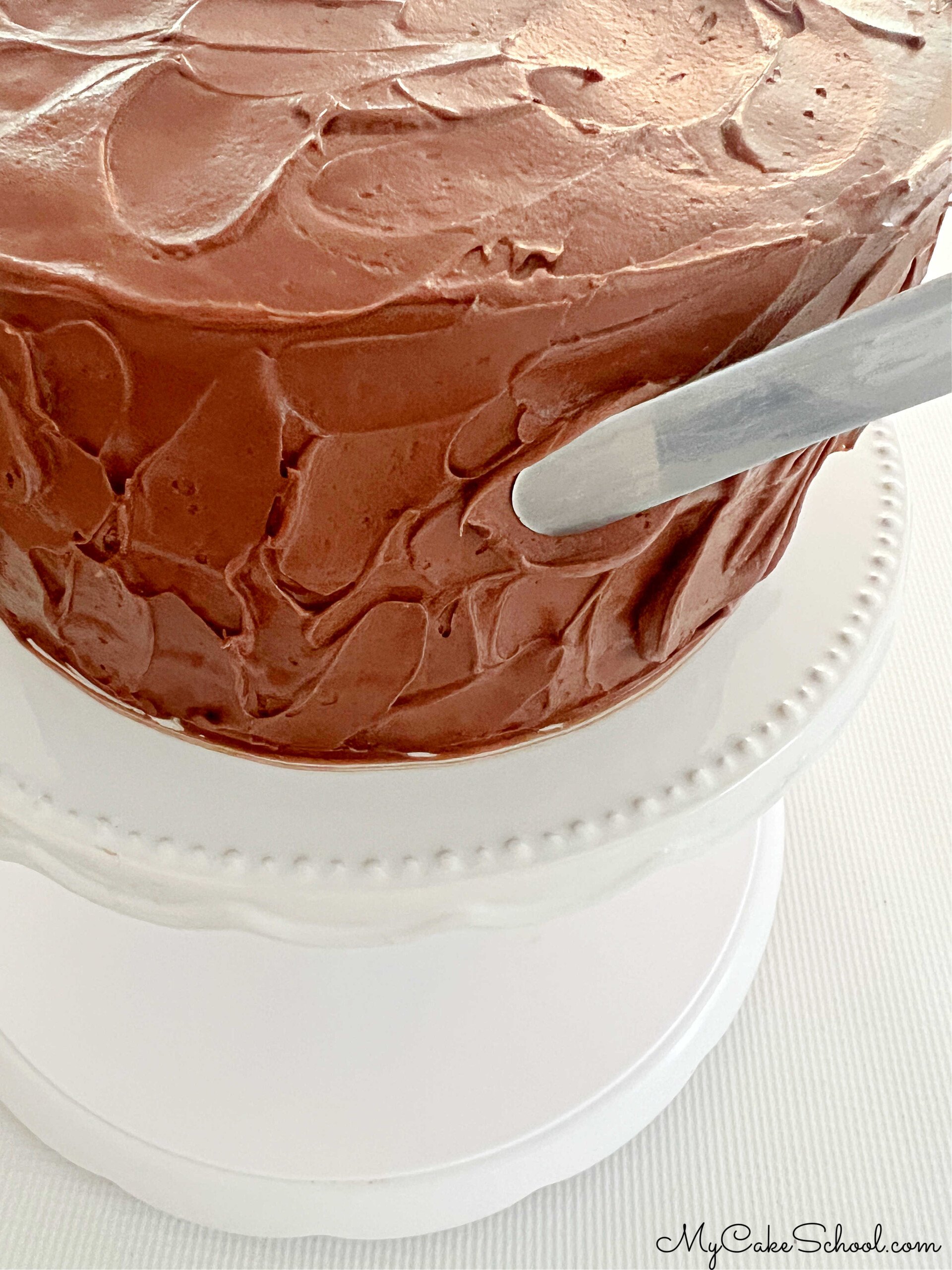 Adding texture to the frosted Chocolate Mousse Cake with an offset spatula.