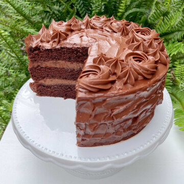 Chocolate Mousse Cake with chocolate frosting, sliced, on a white pedestal.