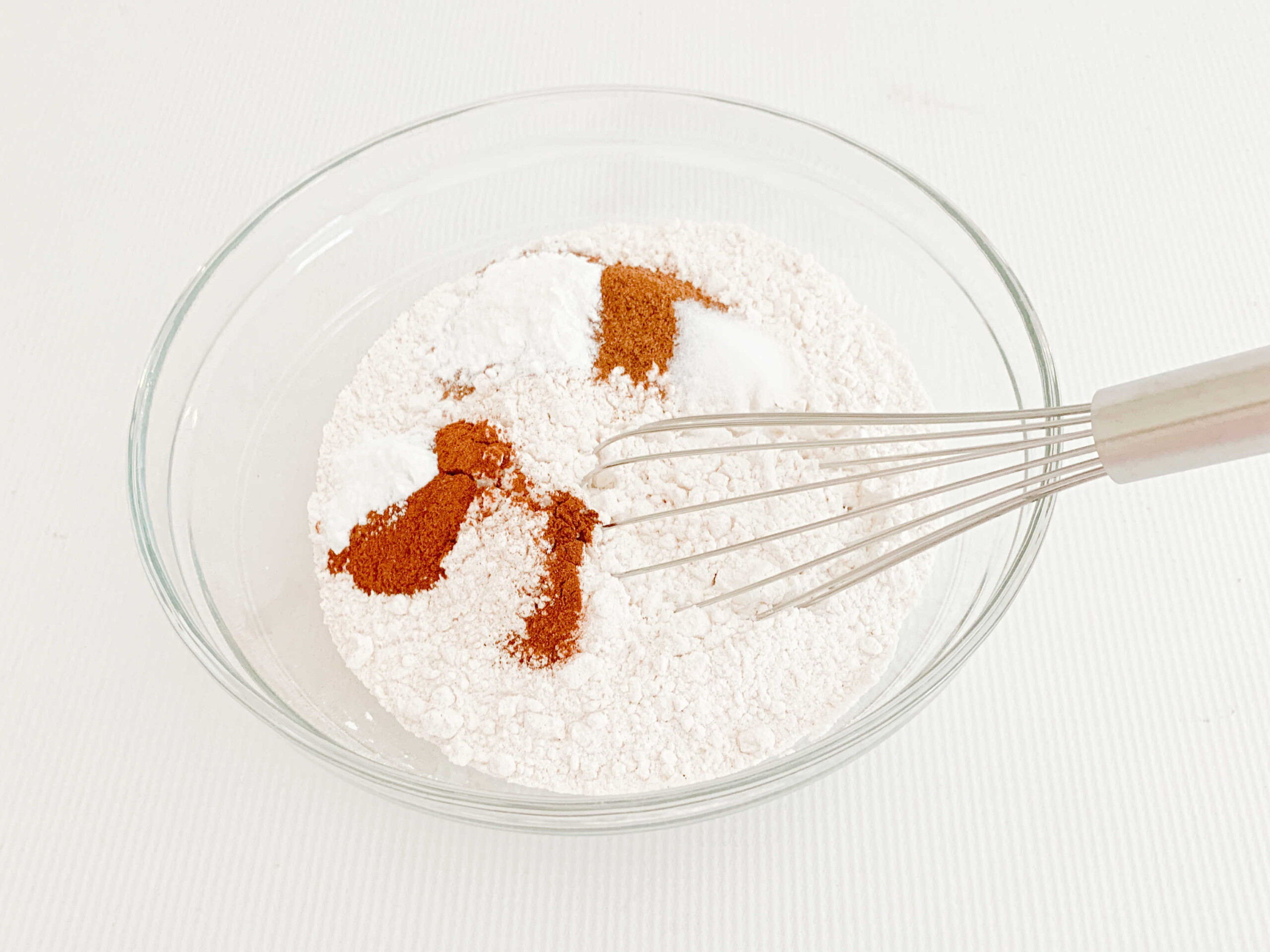 Dry ingredients for pumpkin cupcakes in a bowl with whisk.