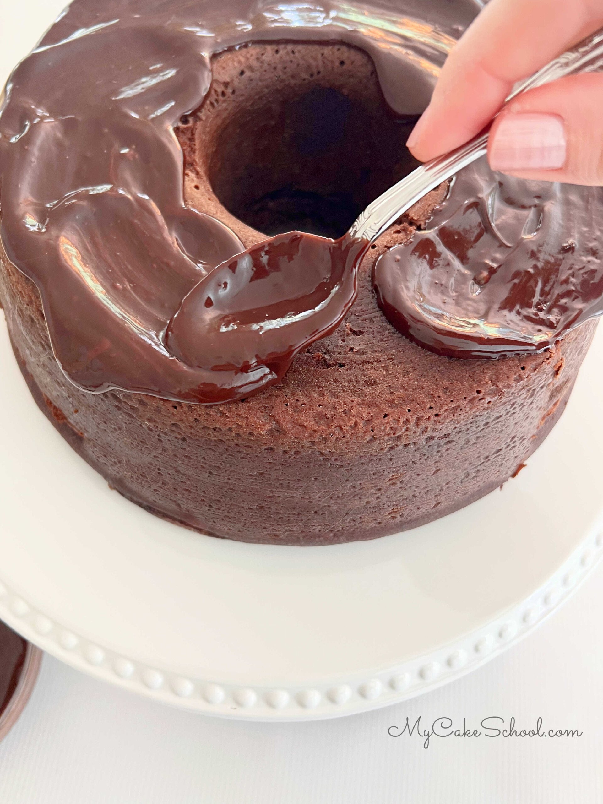 Apply the chocolate glaze to the top of the chocolate bundt cake with a spoon.