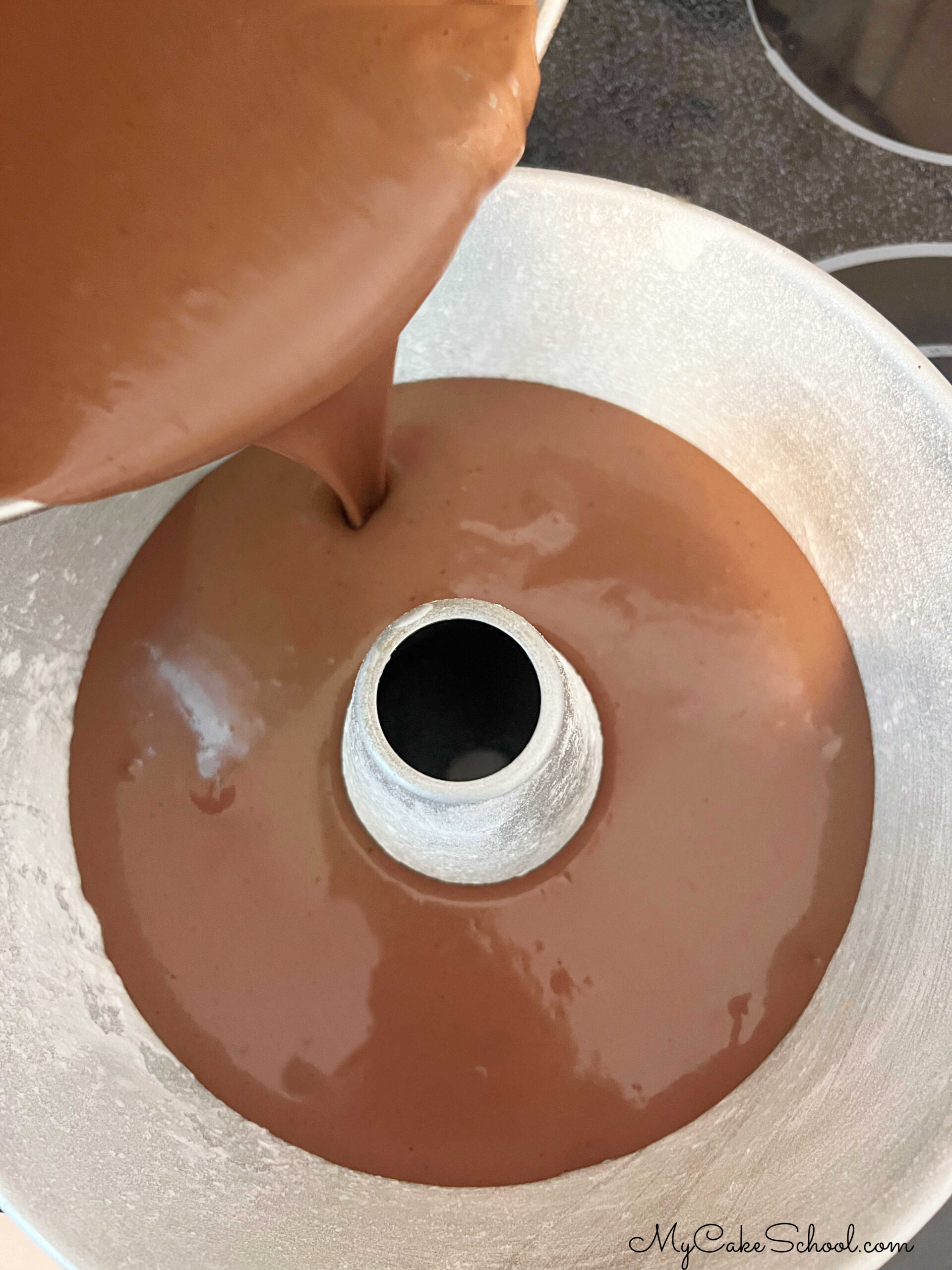 Pouring chocolate bundt cake batter into prepared pan.