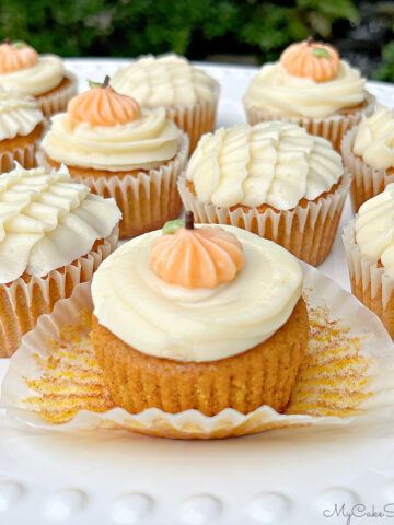 Platter of Pumpkin Cupcakes, frosted with cream cheese frosting and decorative piping.