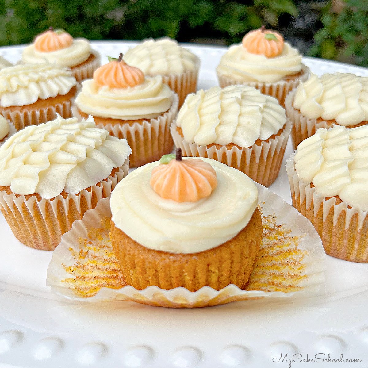 Platter of Pumpkin Cupcakes, frosted with cream cheese frosting and decorative piping.