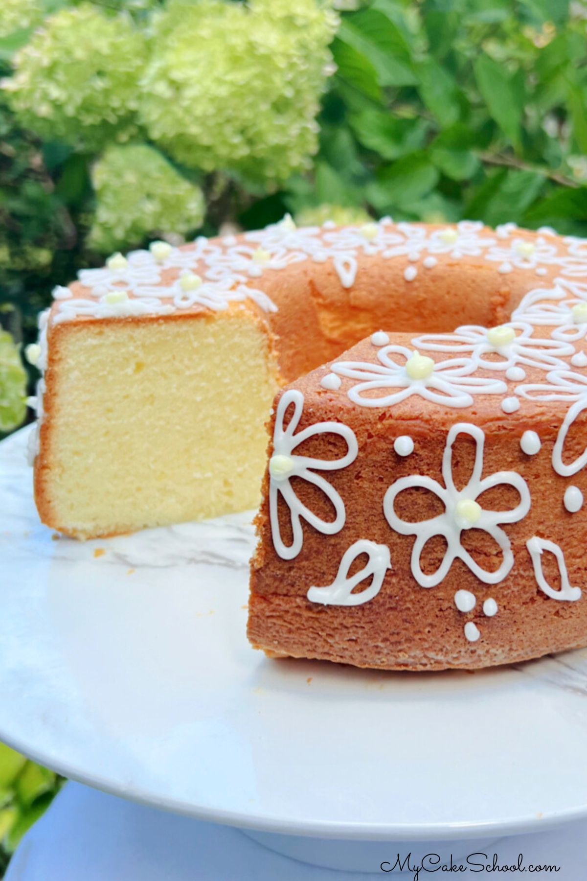 Sliced Lemon Cream Cheese pound Cake on a white pedestal.