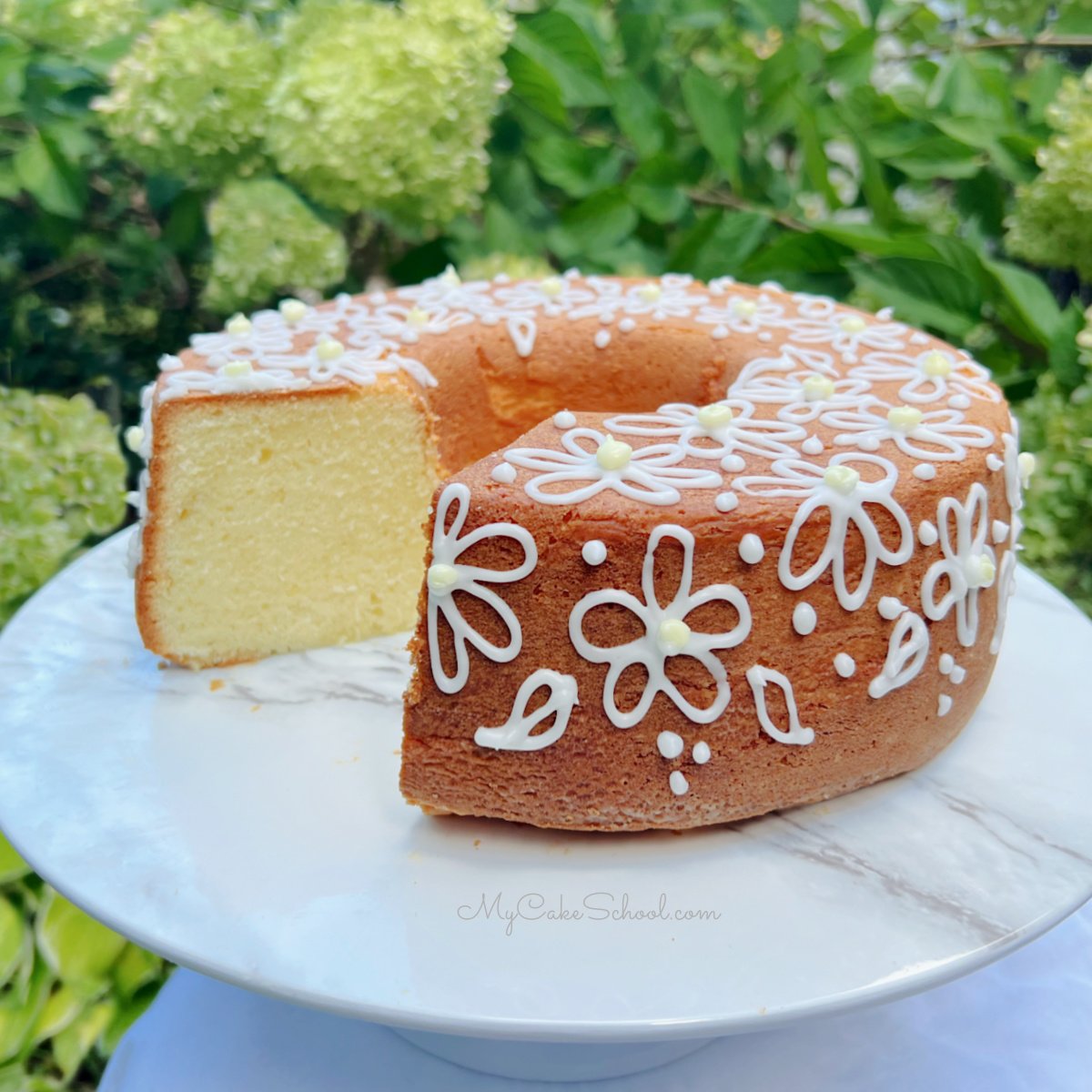 Lemon Cream Cheese Pound Cake, sliced, on a white pedestal.