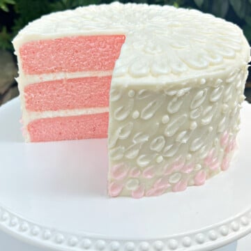 Sliced Pink Velvet Cake on a white cake pedestal.