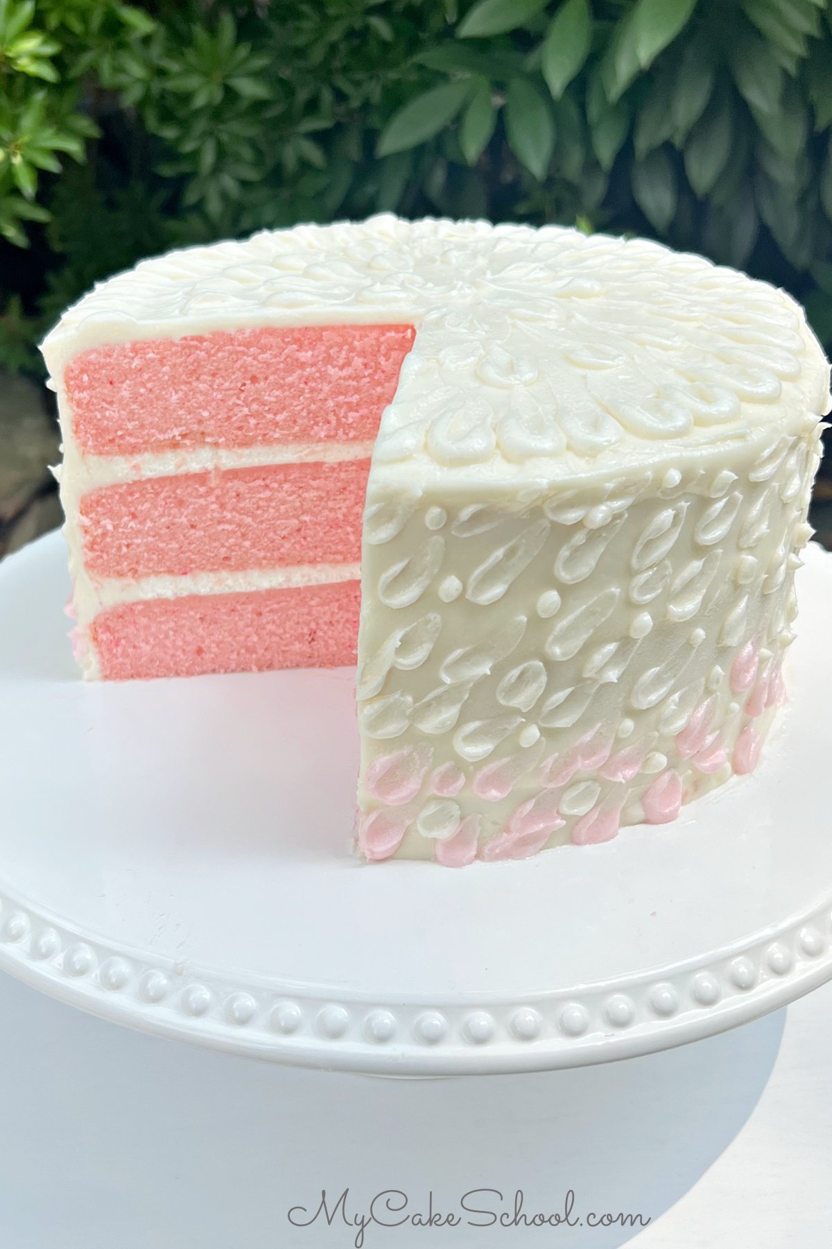 Sliced Pink Velvet Cake on a white cake pedestal.