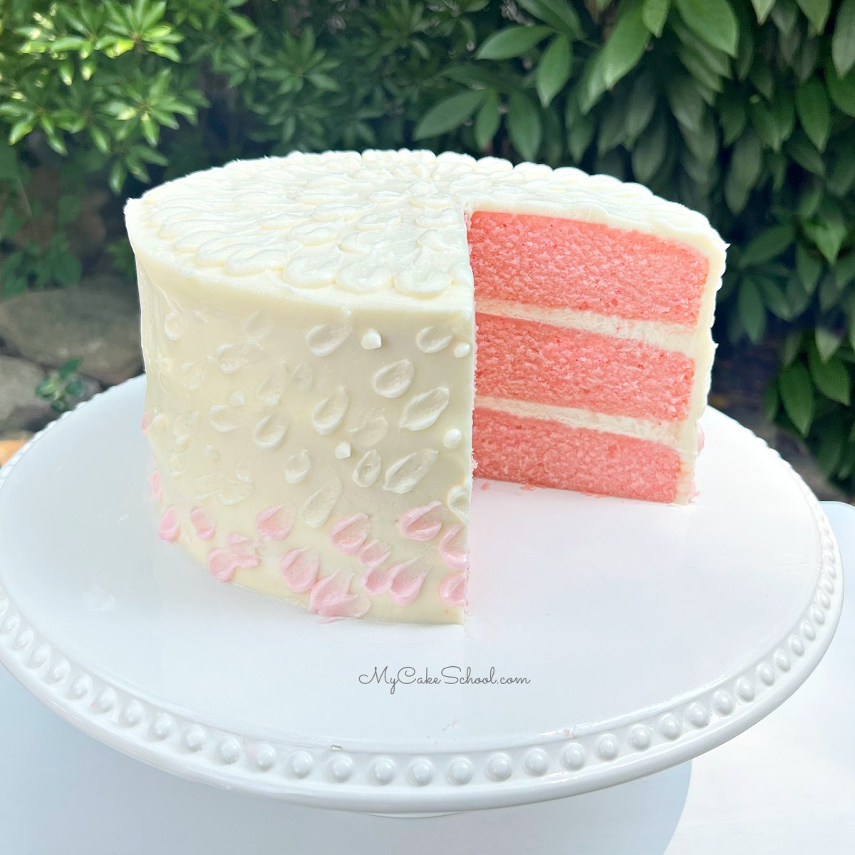 Pink Velvet Cake, sliced on a white pedestal.