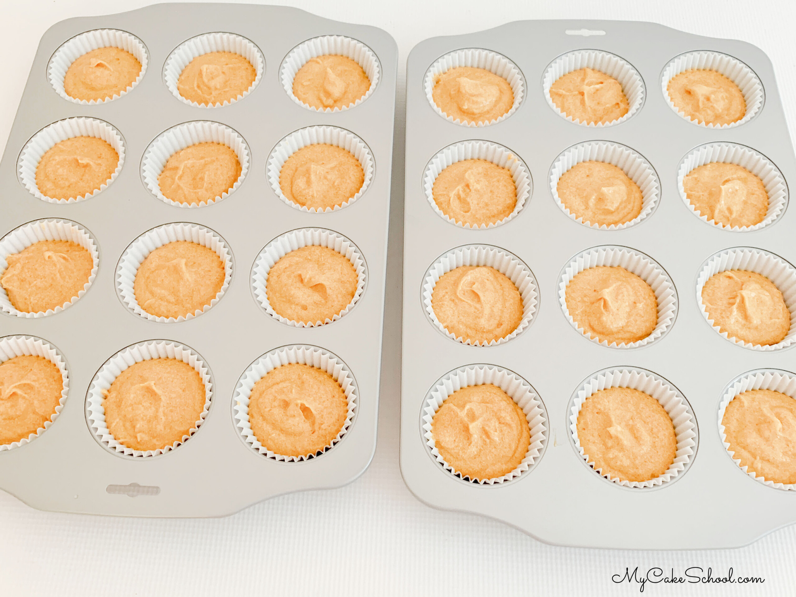 Pumpkin Cupcake Batter in paper liners in pans.