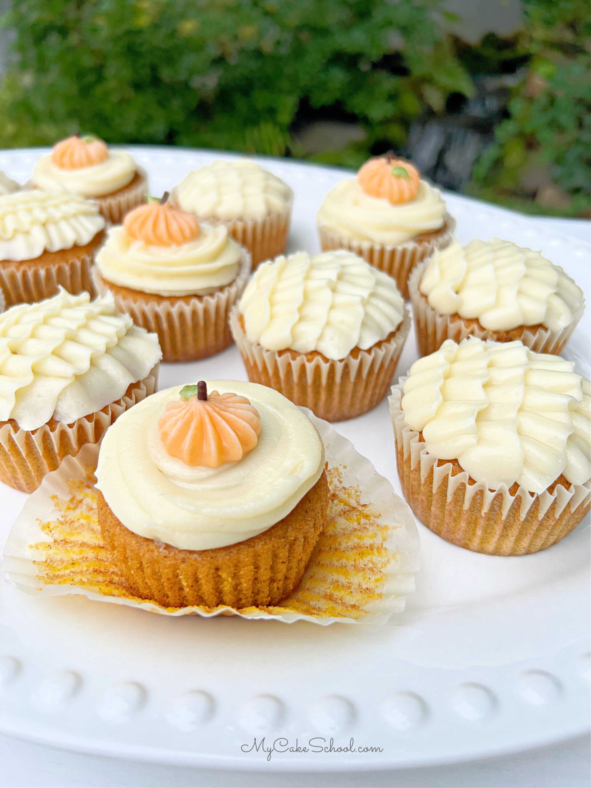 Platter of Pumpkin Cupcakes, topped with cream cheese frosting and piped pumpkins.