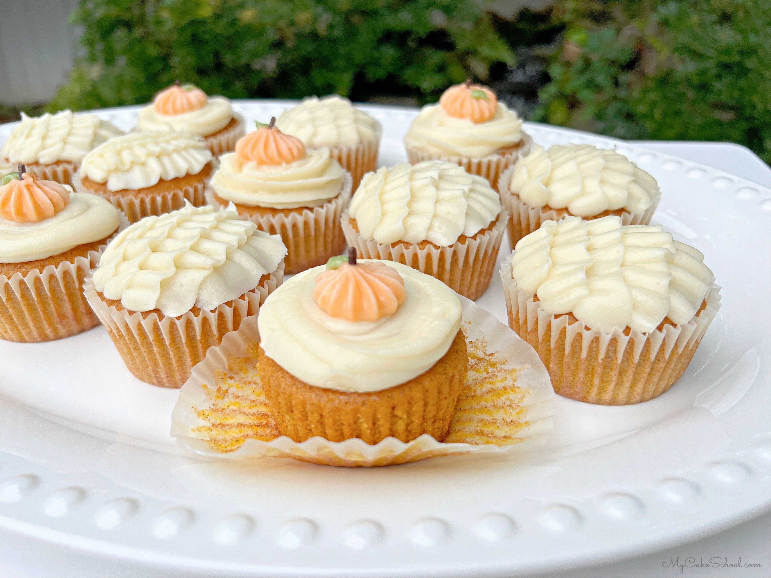 Pumpkin Cupcakes, frosted with cream cheese frosting and piped pumpkin accents.