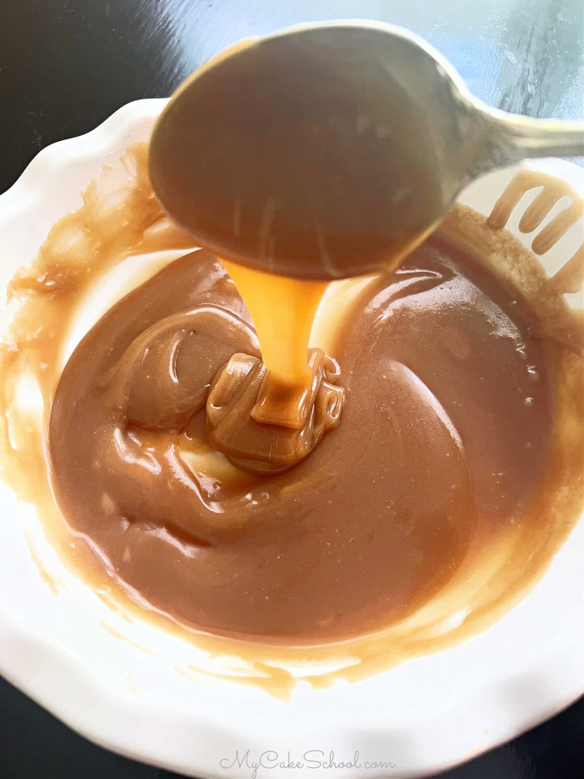 Bowl of homemade caramel sauce, with spoon.