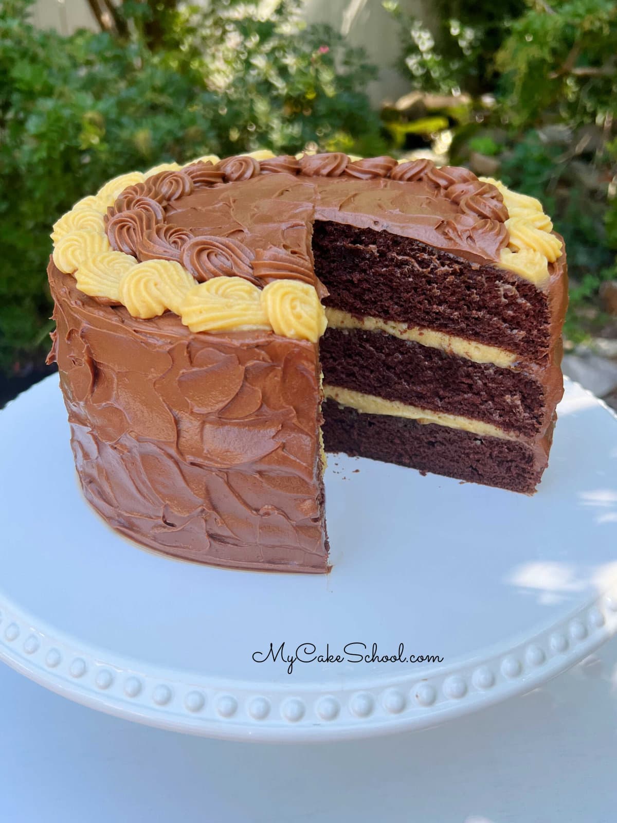 Chocolate Caramel Cake, sliced, on a cake pedestal.