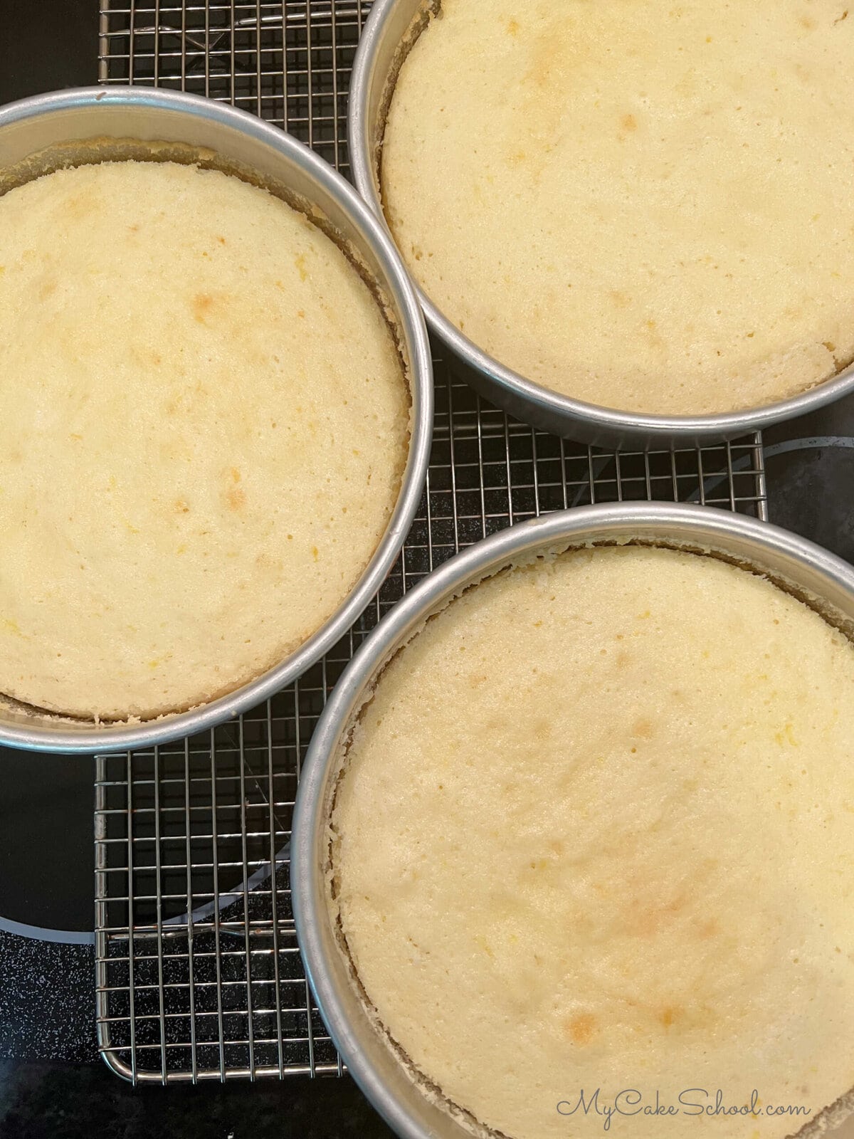 Lemon almond cake layers in cake pans, cooling on wire rack.