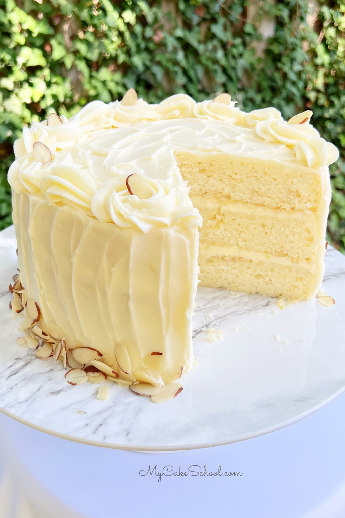 Lemon Almond Cake, sliced, on a cake pedestal.