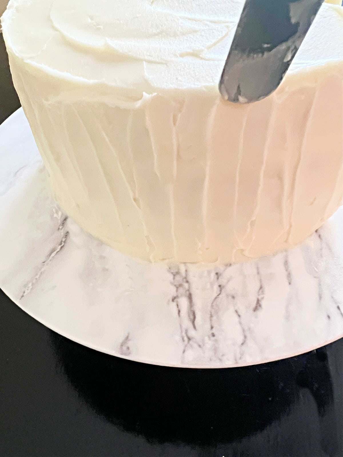 Adding texture to the frosted Lemon Almond Layer Cake using an offset spatula.