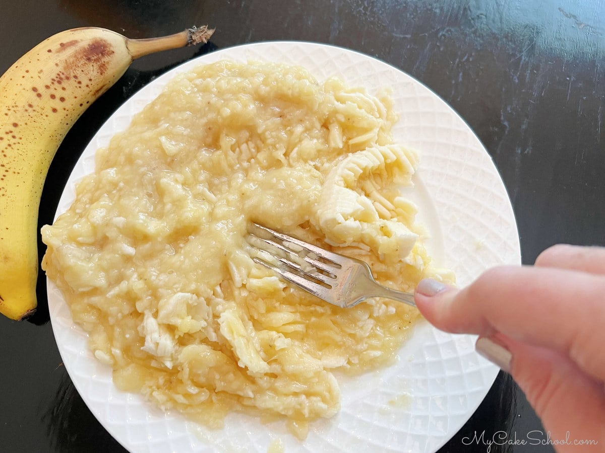 Mashing bananas with a fork on a plate.