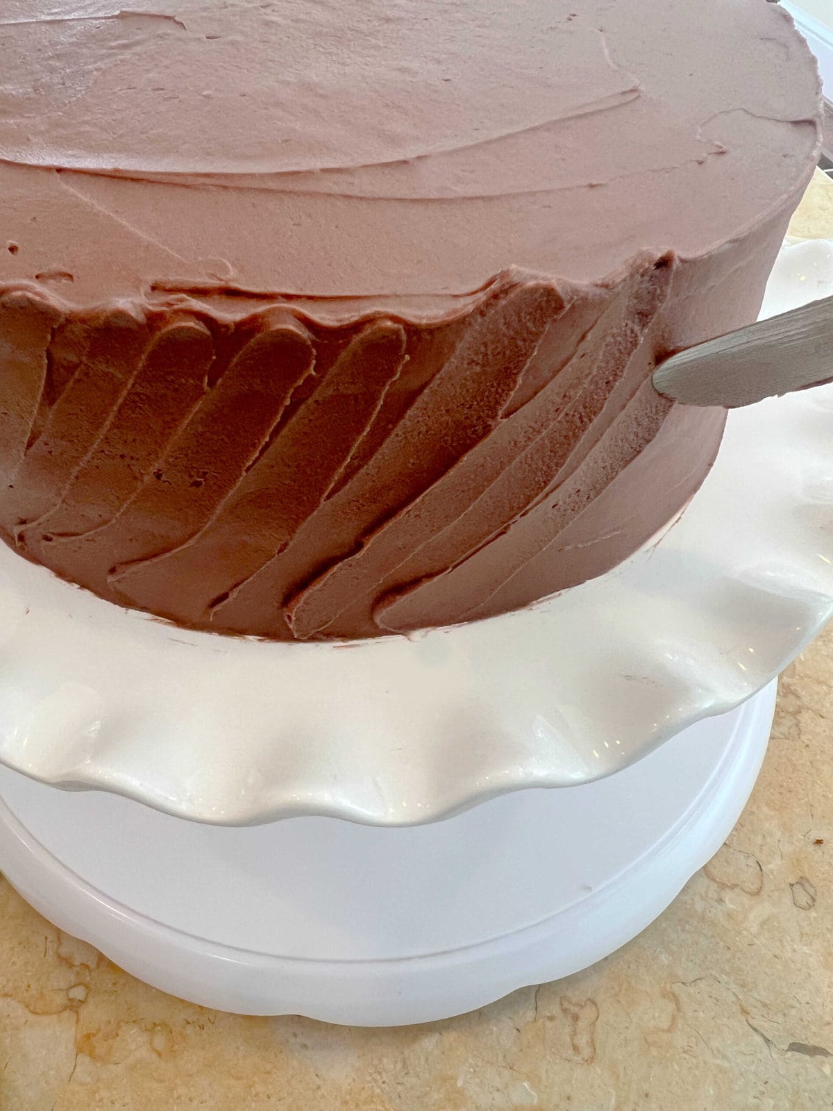 Adding texture to the frosted cake with an offset spatula.