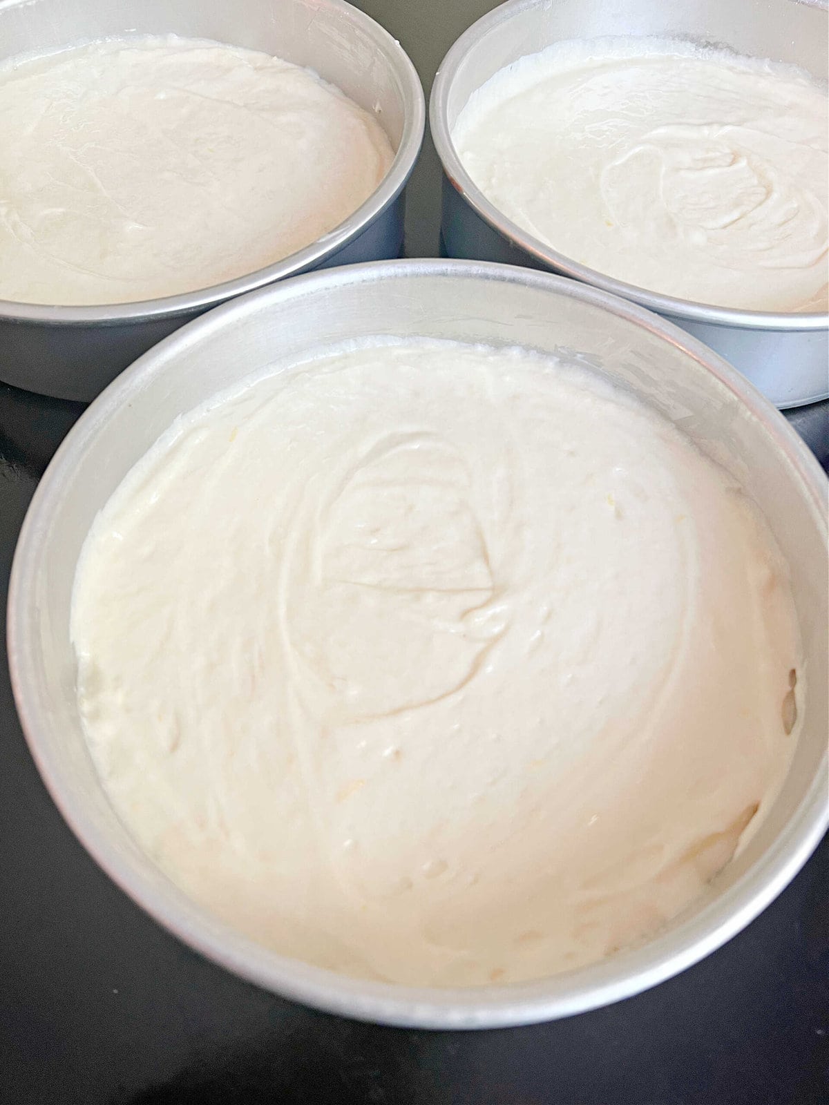 Three cake pans of cake batter.