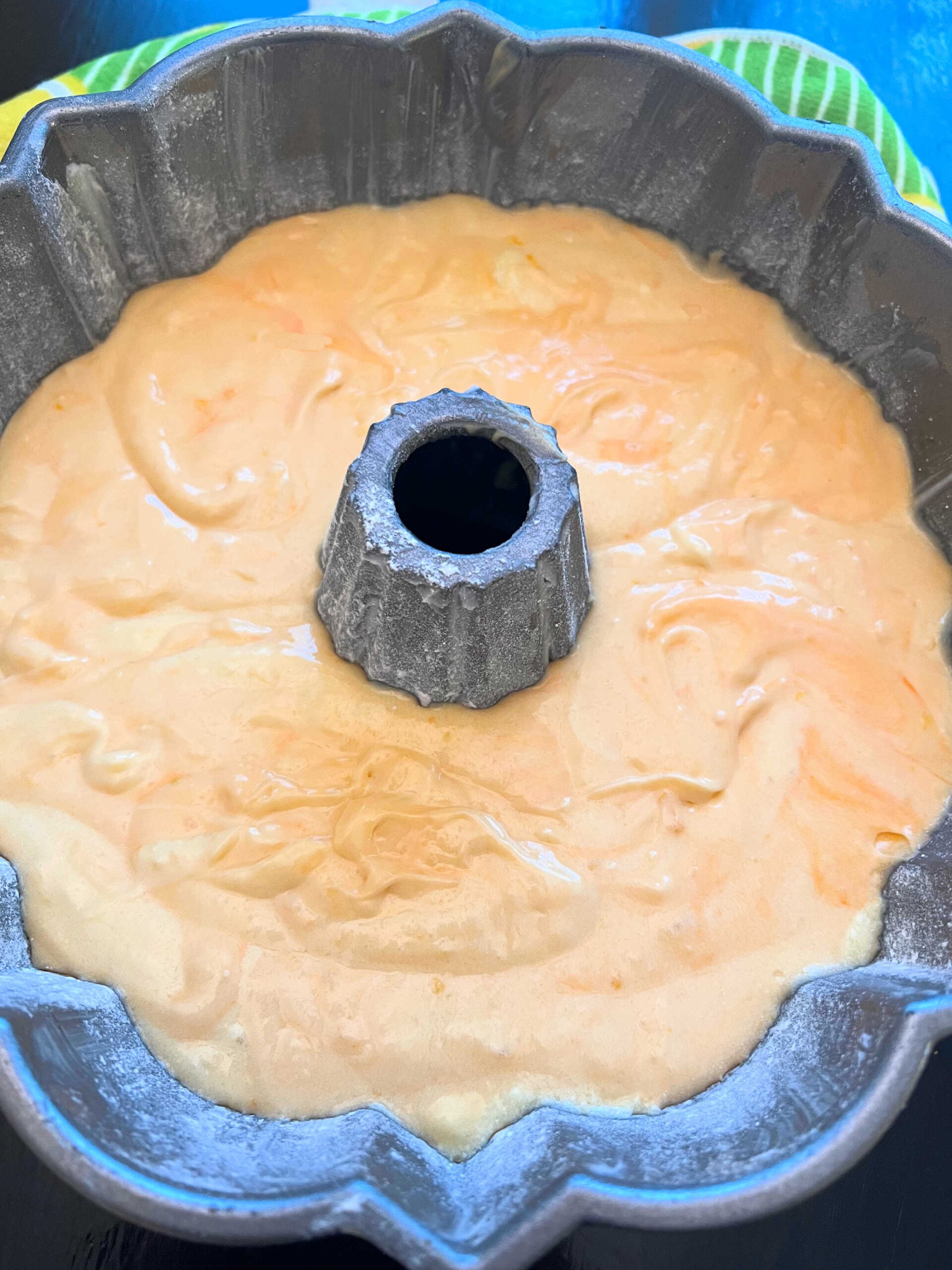Orange bundt cake batter in prepared bundt pan.