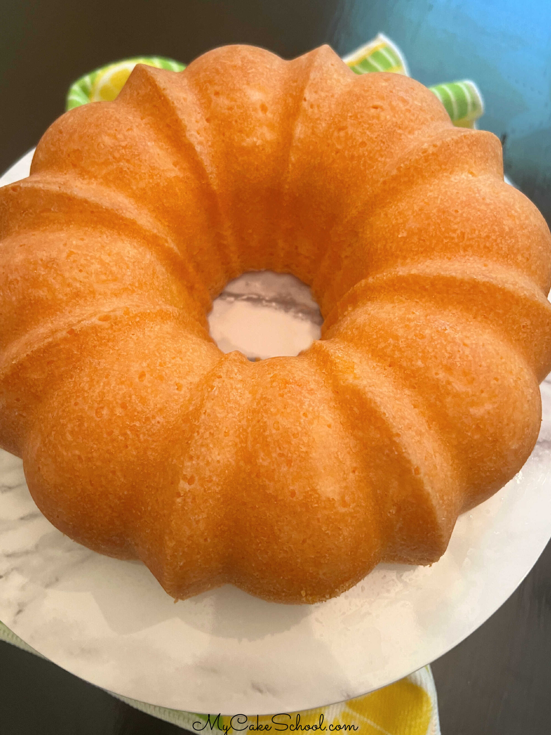 Orange Bundt Cake on a cake pedestal.