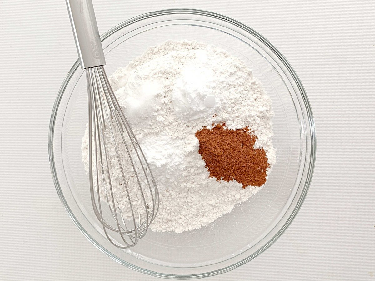 Dry ingredients in a bowl with whisk for applesauce cake.