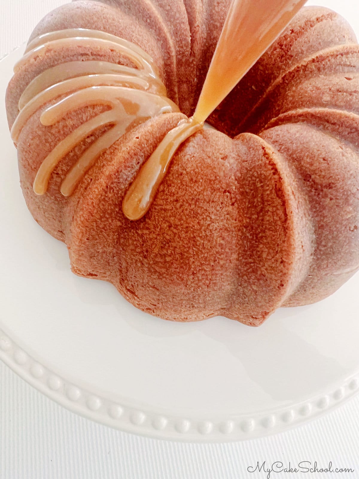 Piping Caramel onto cooled Applesauce Cake using a disposable piping bag with the tip snipped away.